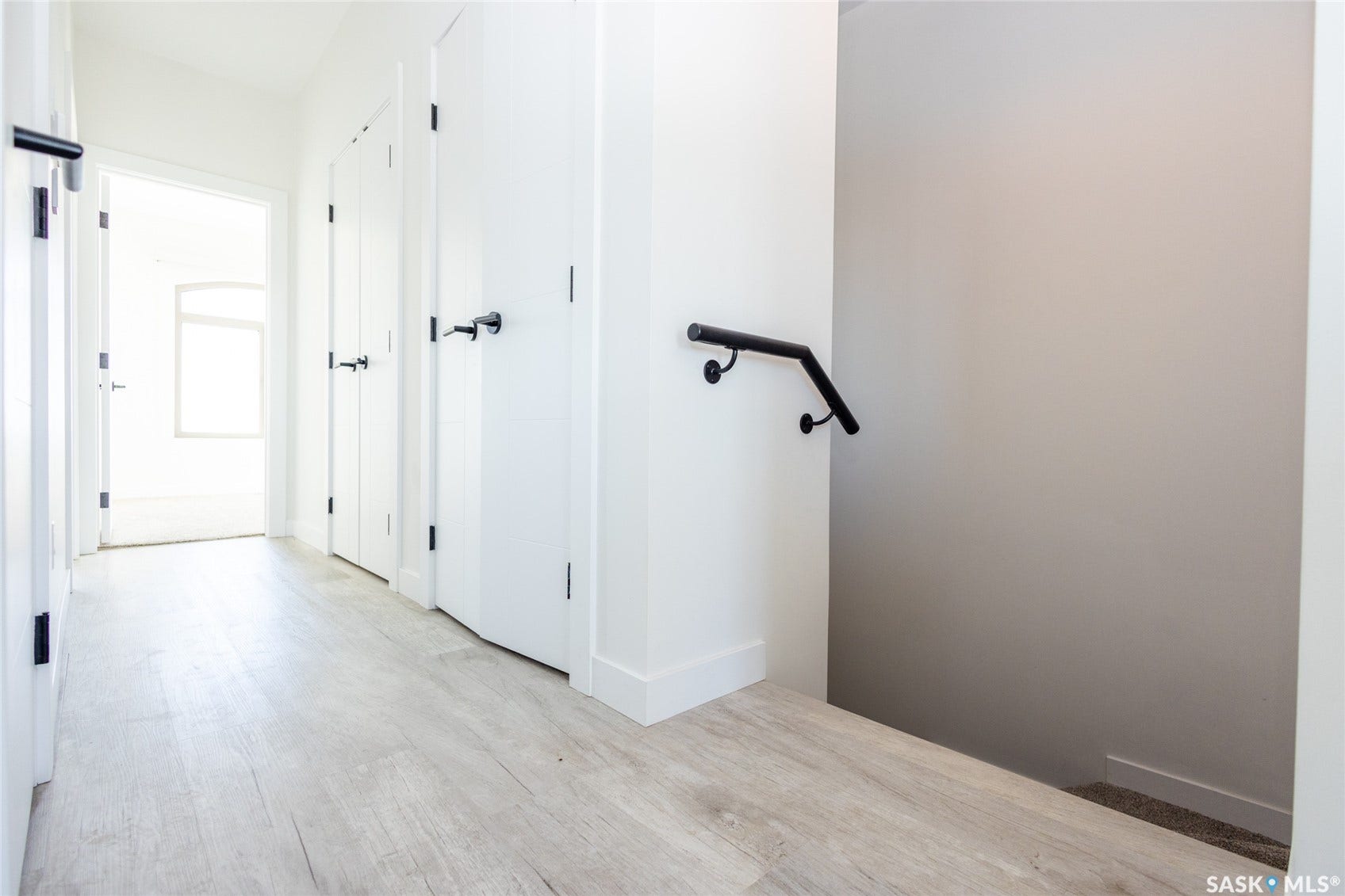 Light wood-finish flooring with white walls and doors