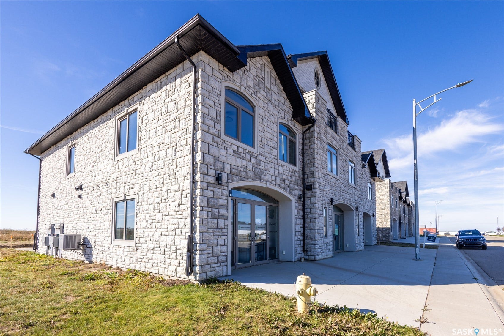 Stone veneer exterior with arched entryways, black-framed windows, and dark soffit detailing