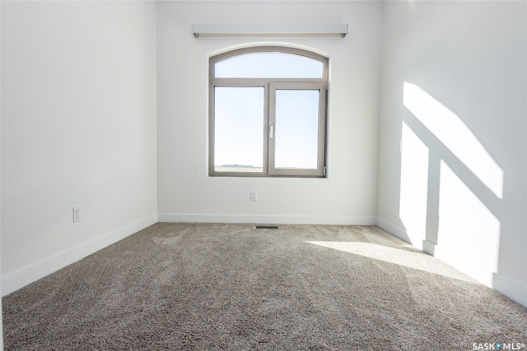 Arched window with gray trim, light tan carpeting, and white walls