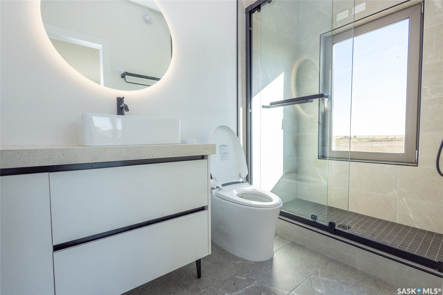 Modern vanity with a rectangular vessel sink, back-lit circular mirror, and matte black faucet