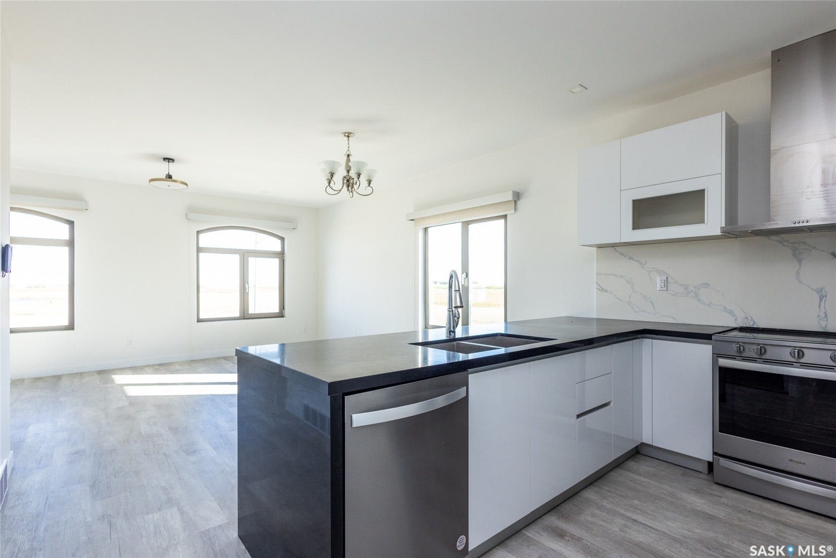 Open-concept kitchen with a dark countertop island, stainless steel appliances, and white cabinetry