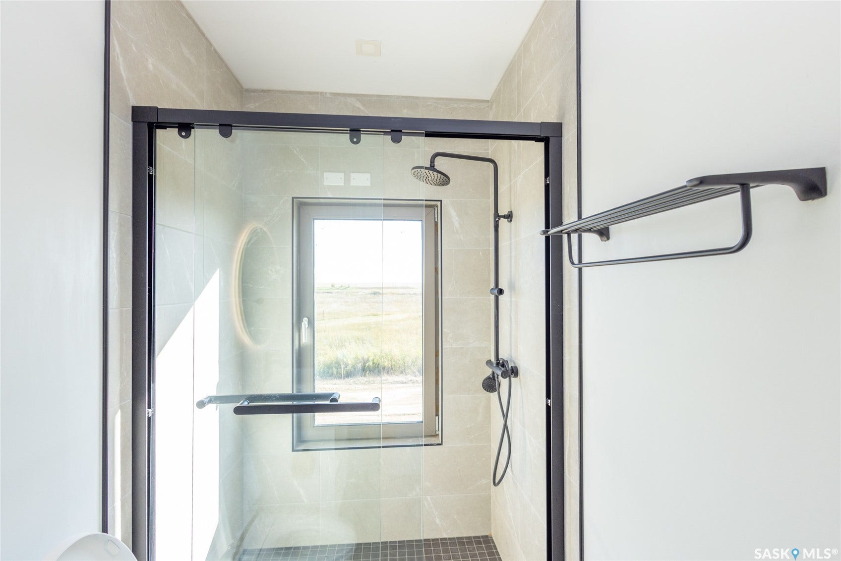 Shower enclosure with black-framed glass, rainfall showerhead, handheld shower, and a built-in window