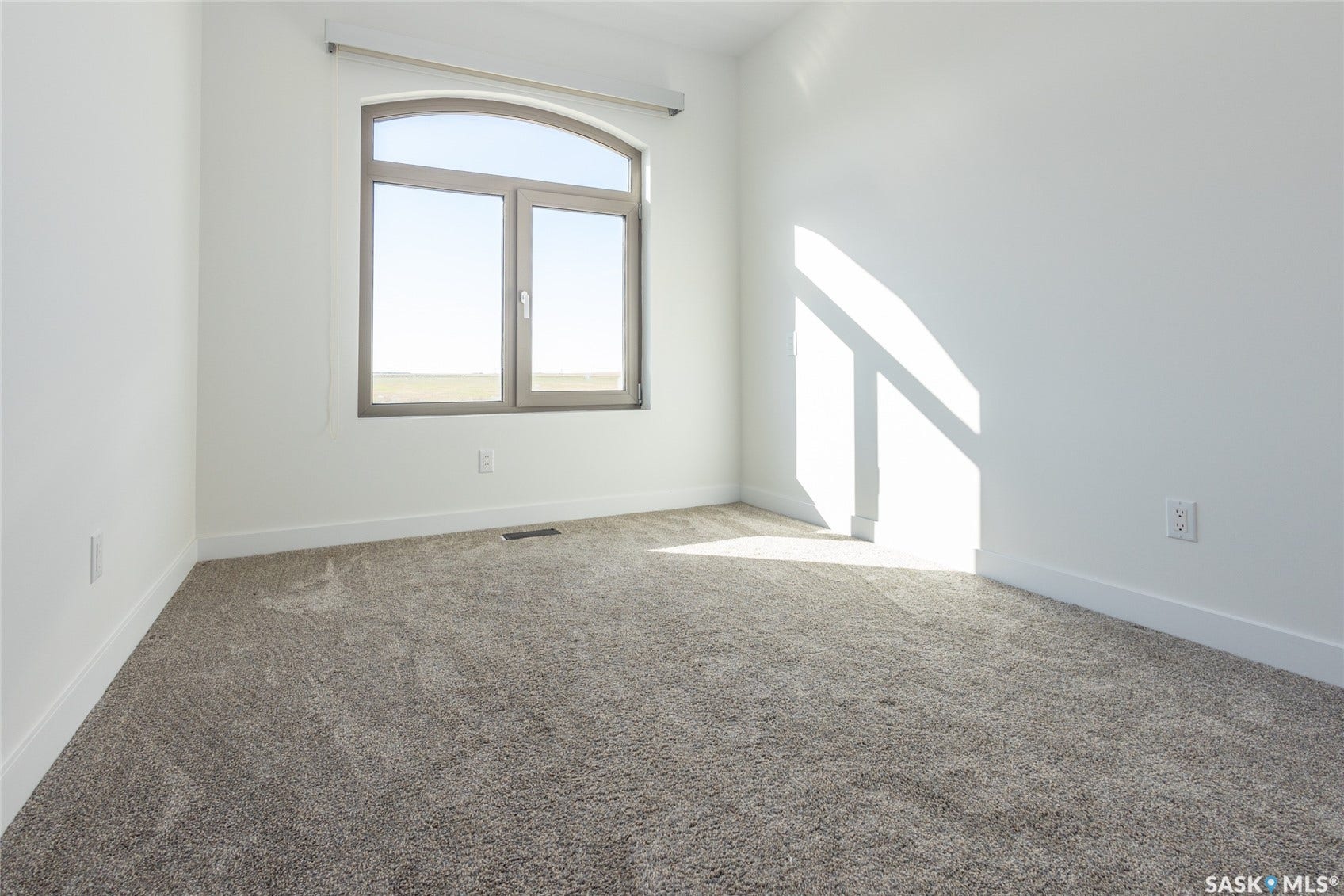 Arched window with gray frame, white walls, and gray carpeting