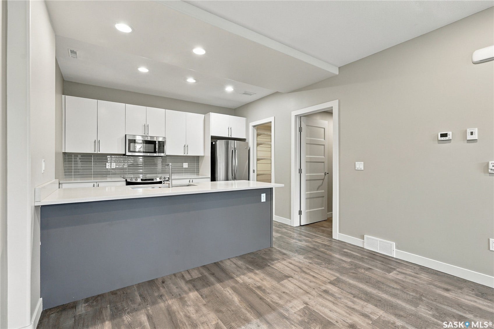Modern kitchen featuring white cabinetry, stainless steel appliances, a white countertop, a gray tile backsplash, and recessed lighting
