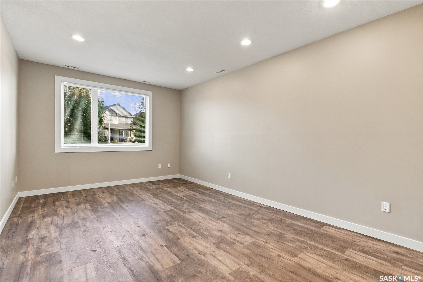 Spacious room featuring wood-finish flooring, recessed lighting, and a large window