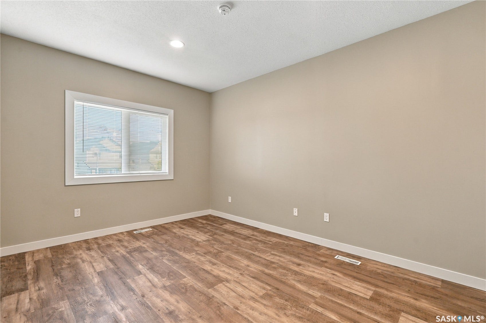 Wood-finish flooring, recessed ceiling lighting, and a window with horizontal blinds