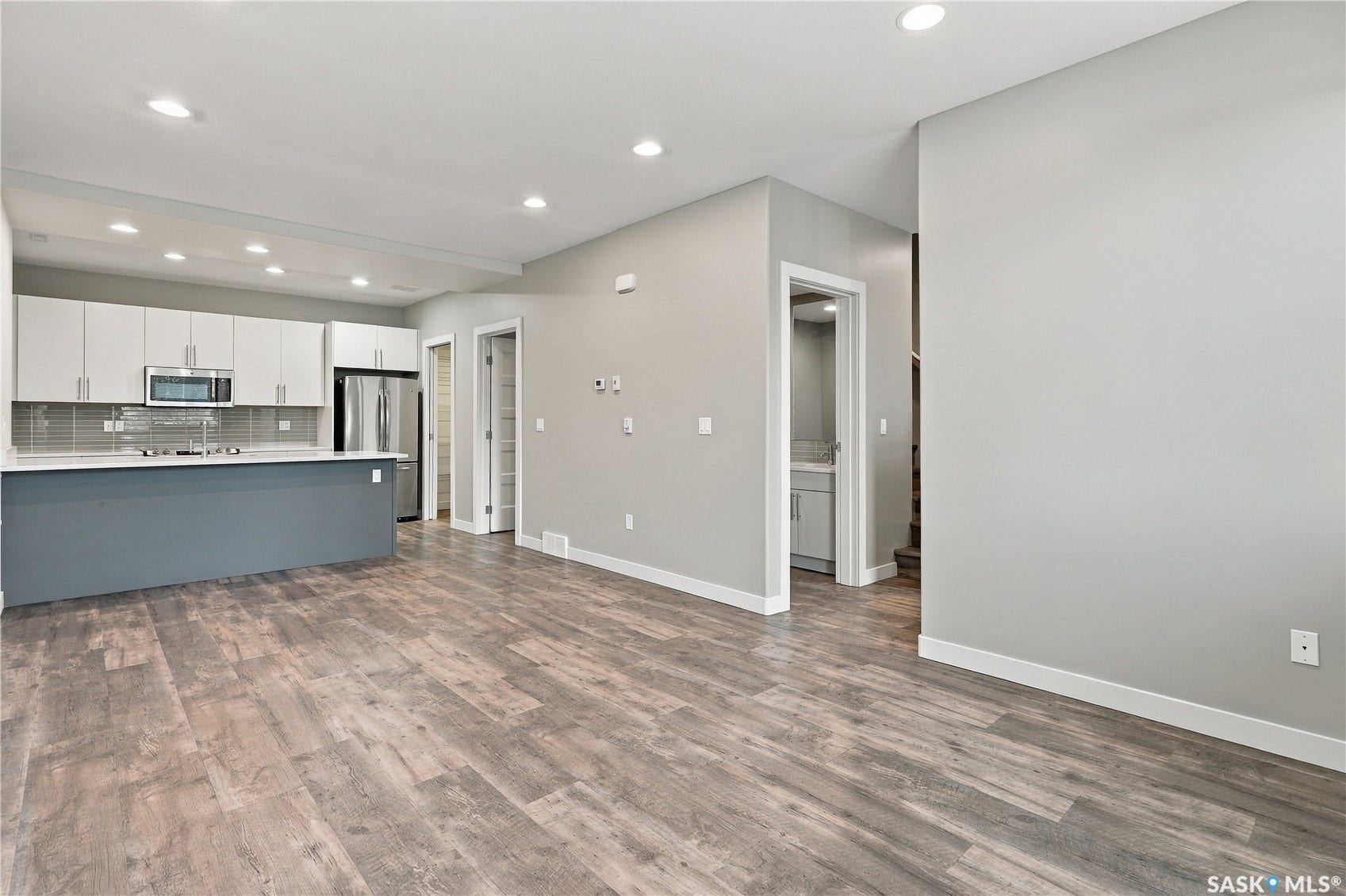 Kitchen featuring flat-panel cabinetry, stainless steel appliances, a tiled backsplash, and a large island with contrasting blue base cabinetry