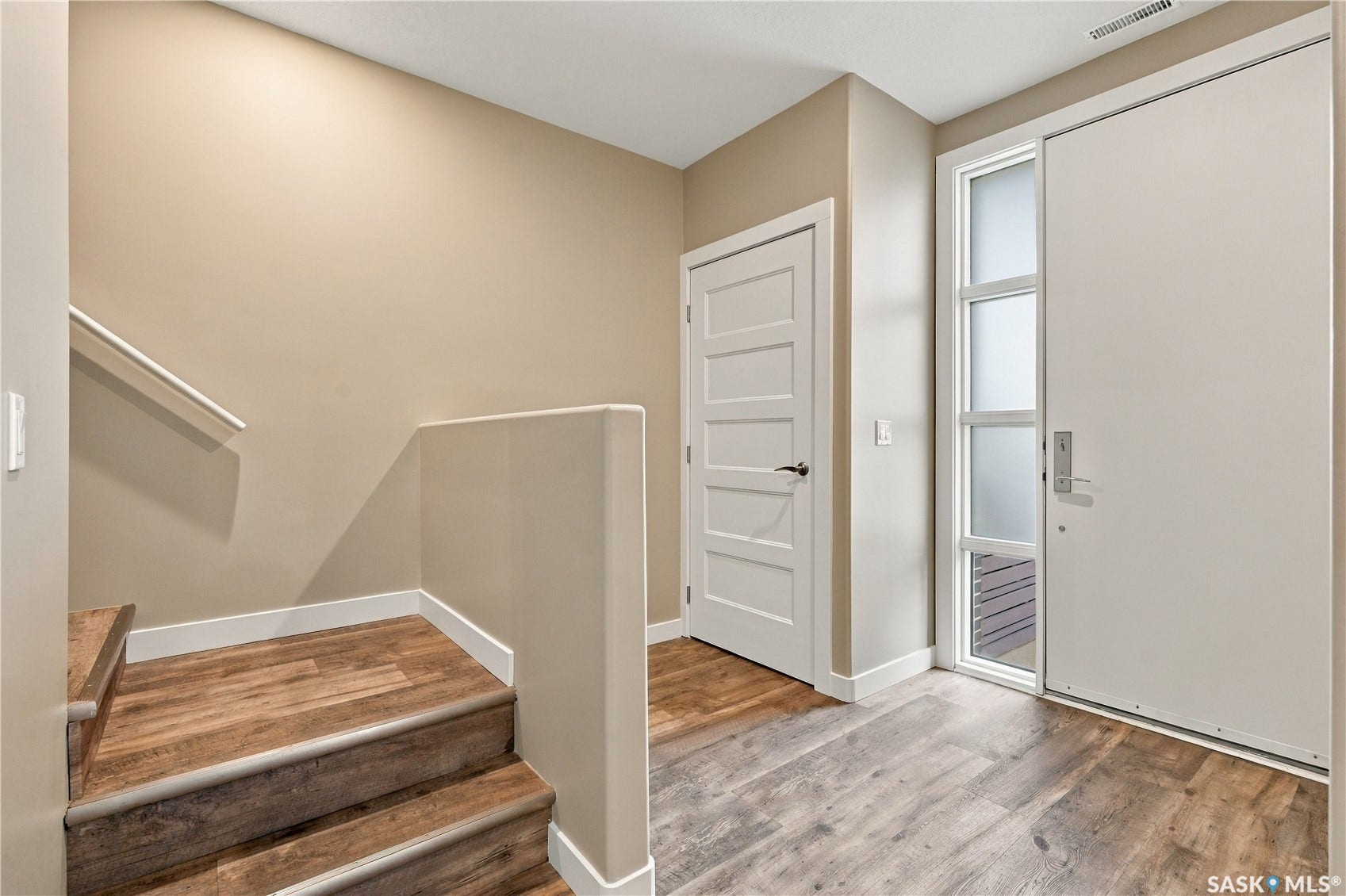 Wood-finish flooring throughout, bright white trim, paneled interior doors, and a modern entry door with a frosted glass sidelight