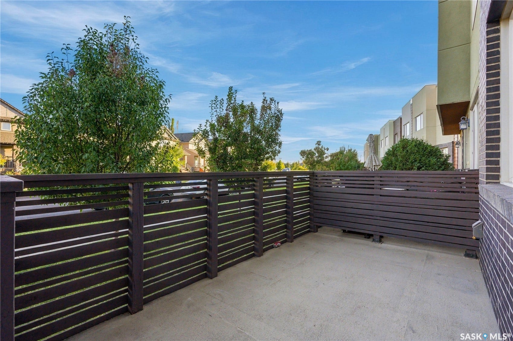 Private outdoor patio featuring a concrete surface and horizontal slat fencing