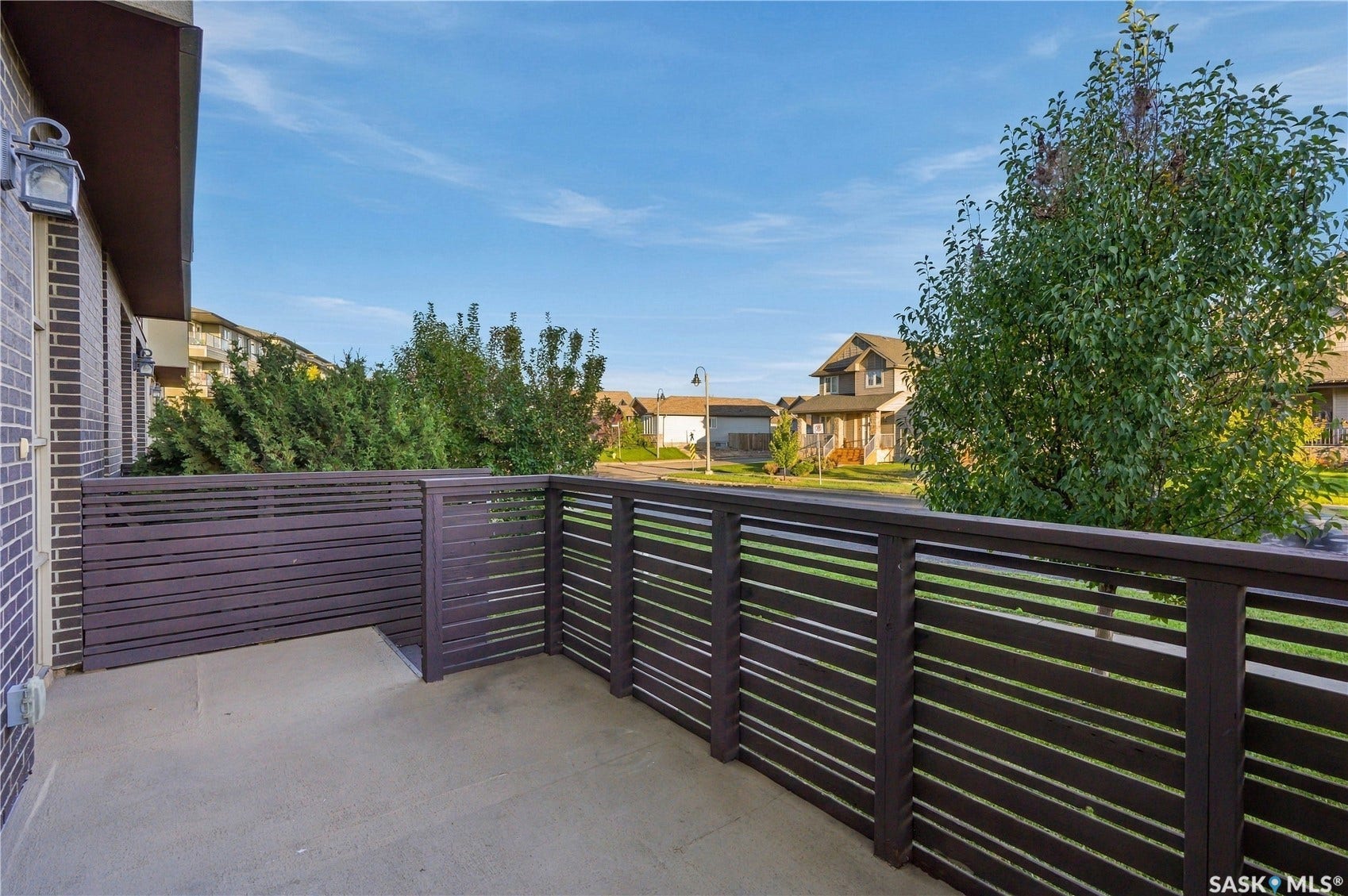 Outdoor balcony featuring a concrete surface and slatted dark wood-finish fencing