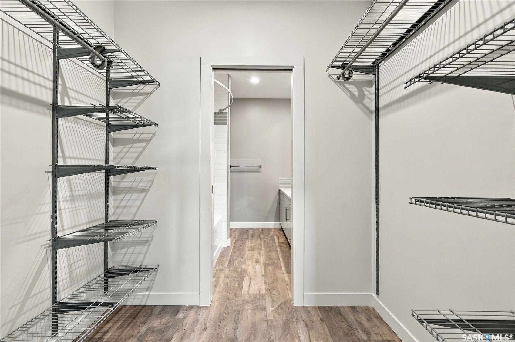 Walk-in closet featuring wire shelving systems, wood-finish flooring, and a white trim doorway