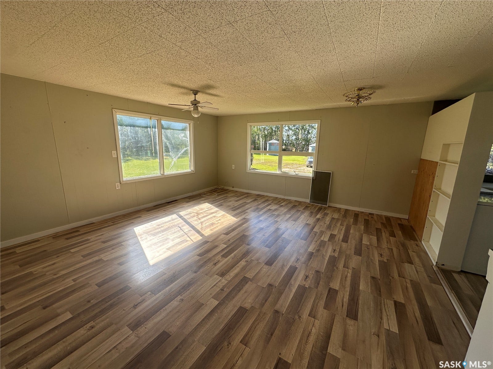 Wood-finish flooring throughout, multiple windows, built-in shelving, and two ceiling light fixtures