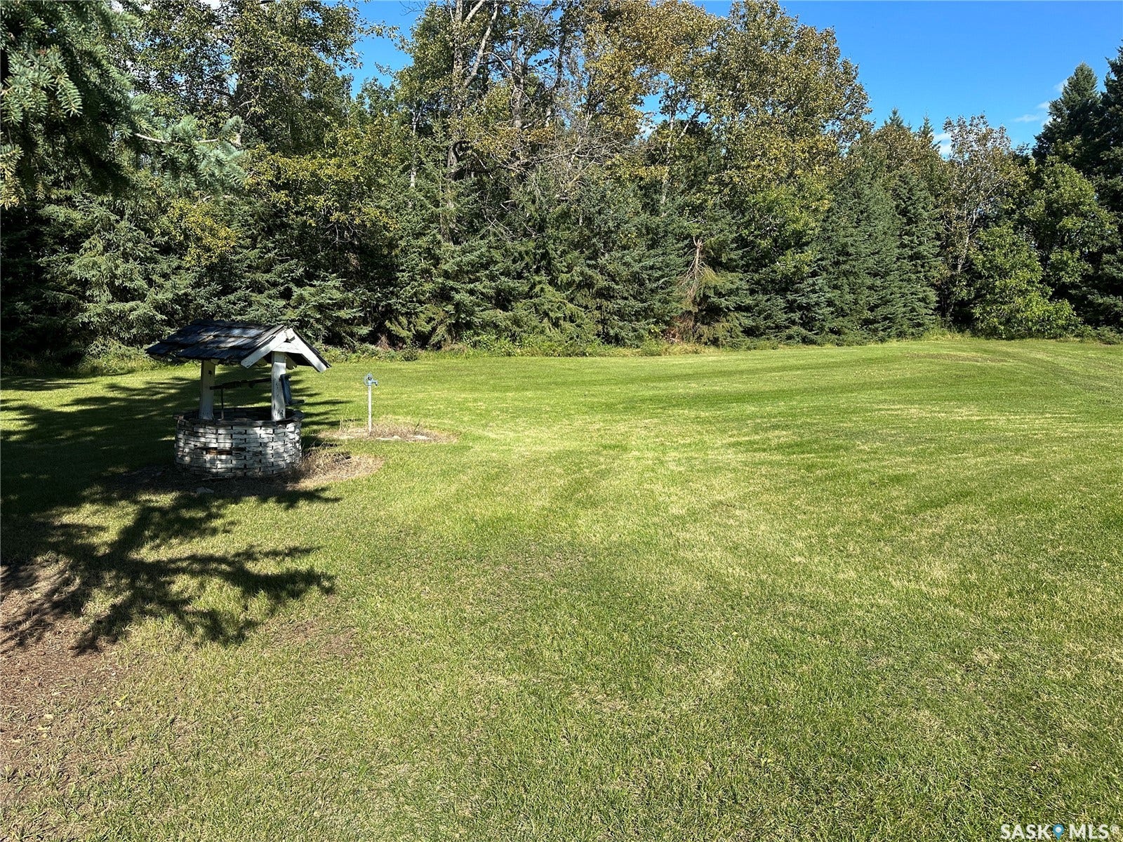 Expansive green lawn with mature trees and a decorative stone well