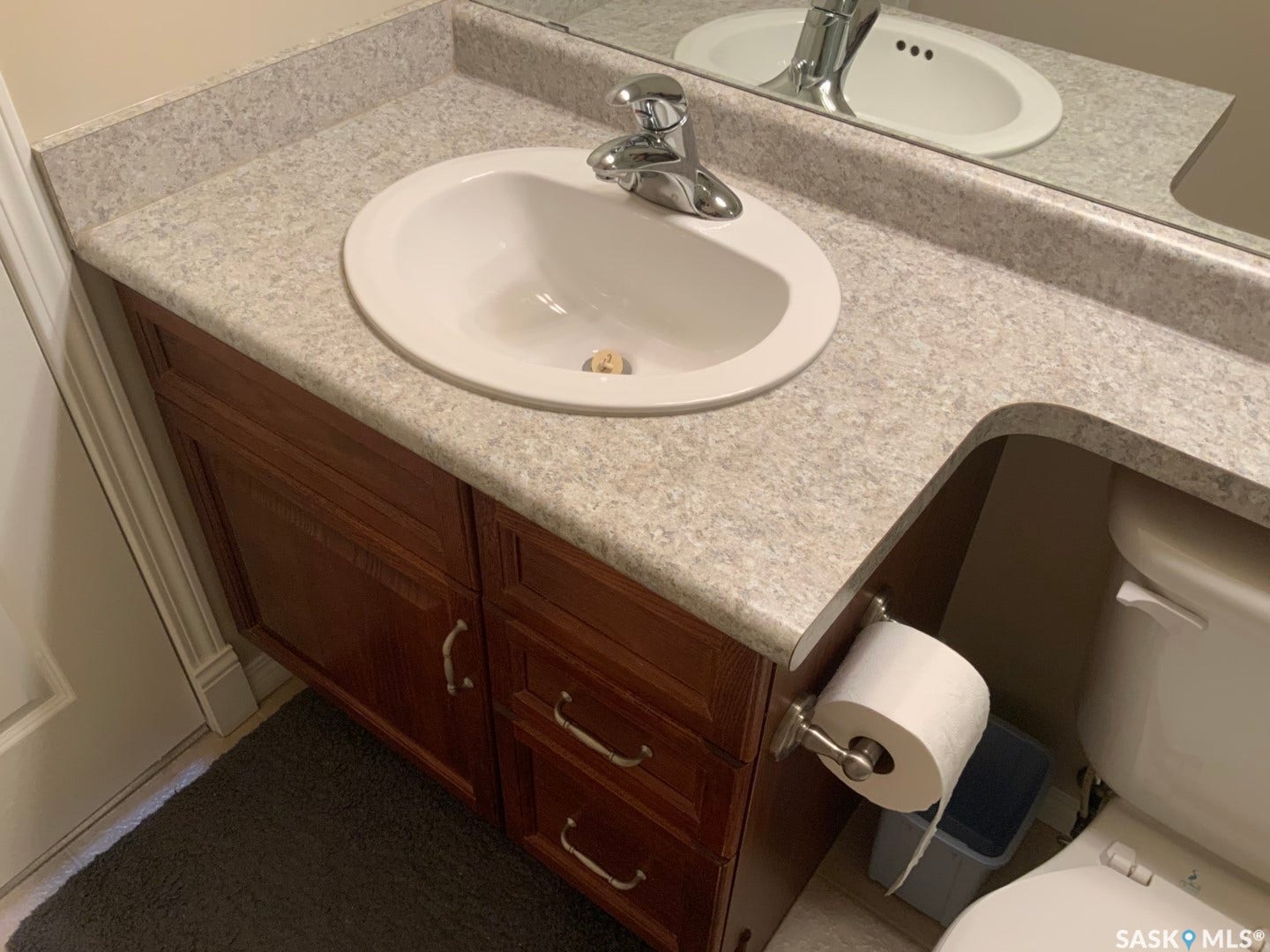Vanity with an integrated sink, polished chrome faucet, and wood-finish cabinetry featuring pull handles