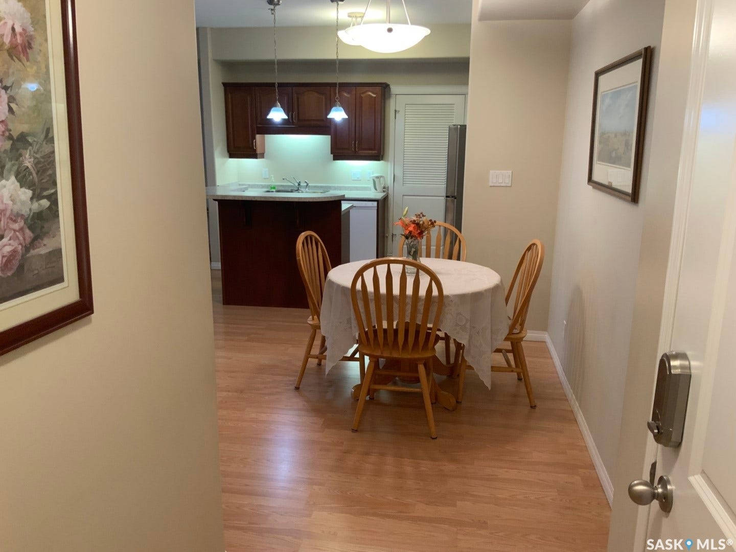 Wood-finish flooring throughout, featuring a kitchen with dark wood cabinetry and a pass-through counter