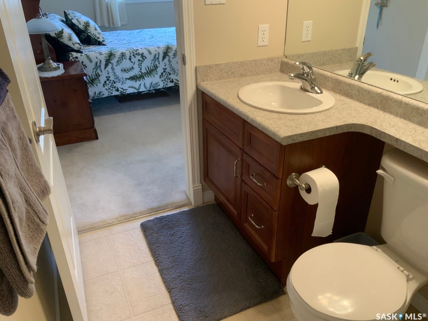 Bathroom featuring a vanity with an integrated sink, a large wall-mounted mirror, a two-piece toilet, and tile flooring