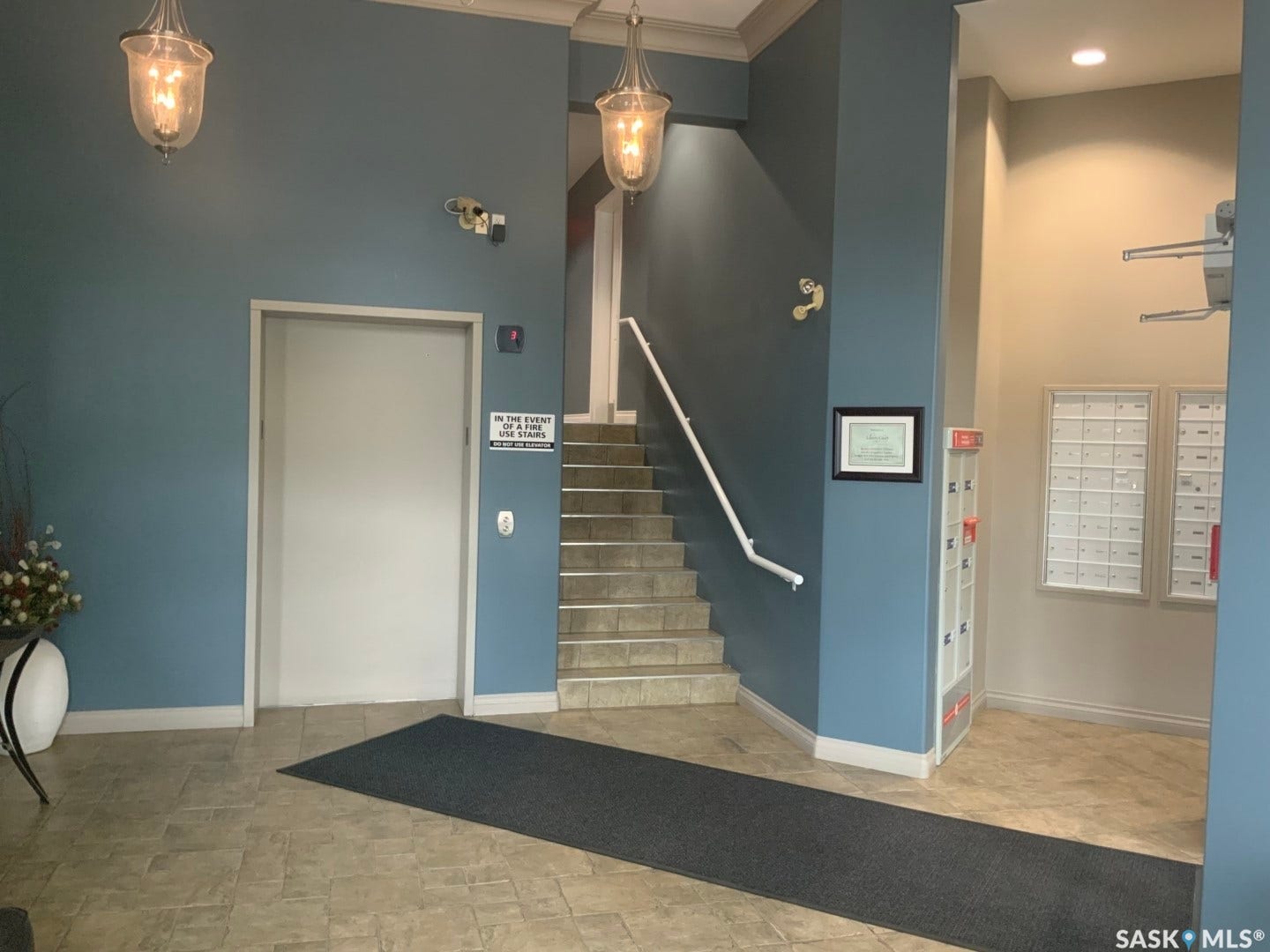 Tiled flooring, overhead light fixtures, and a staircase with a handrail