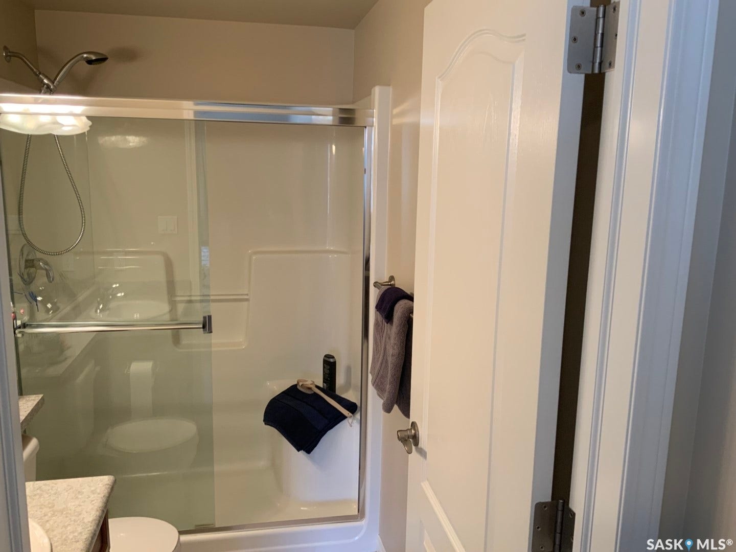 Glass-enclosed shower with a chrome shower head and fixtures, featuring a built-in shelf