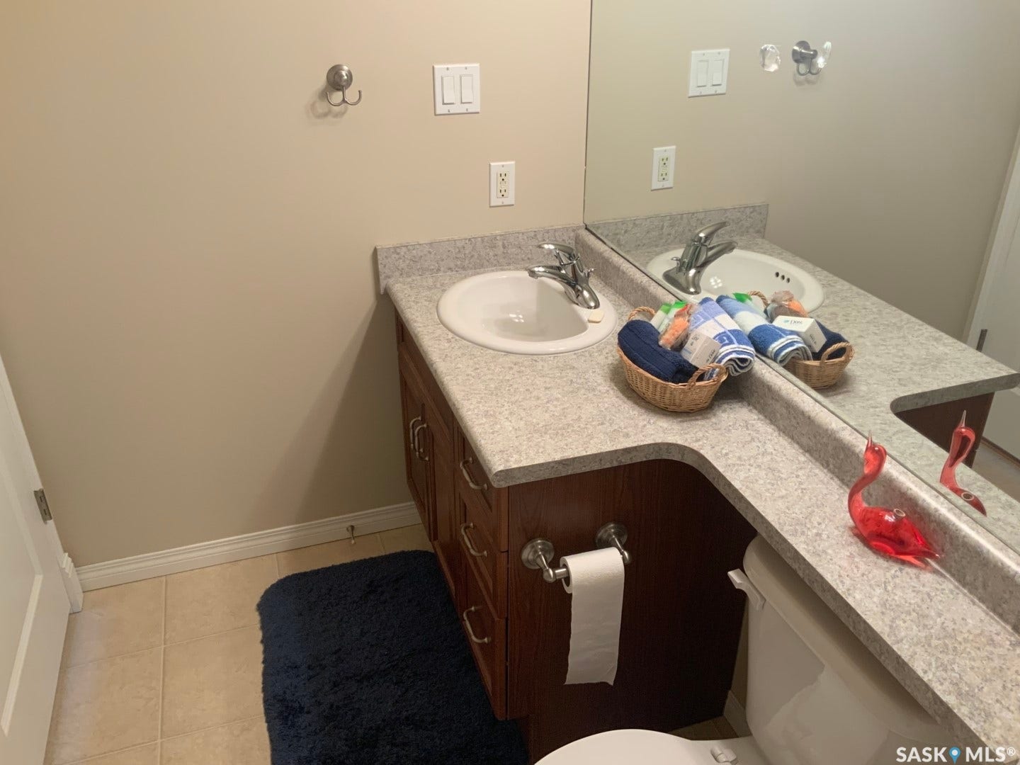Double vanity with integrated sinks and chrome faucets, set on a wood-finish cabinet with multiple drawers and doors, complemented by a light-toned countertop and large wall-mounted mirror