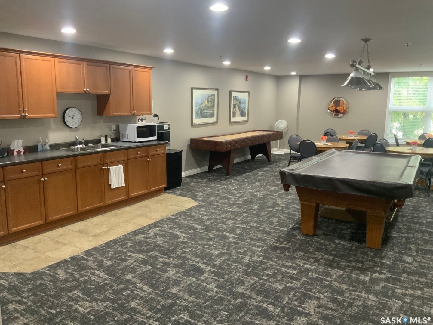 Full kitchen area with wood-finish cabinetry, dark countertops, and stainless steel sink