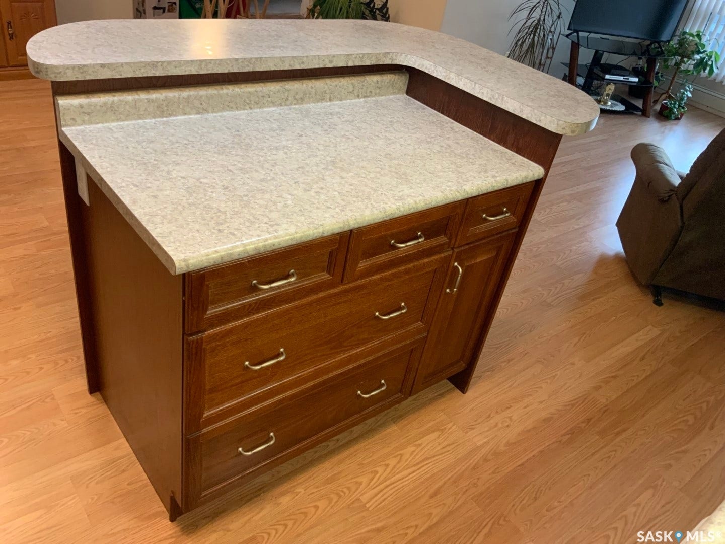 Kitchen island with a light-toned countertop, wood-finish cabinetry, and wood-finish flooring