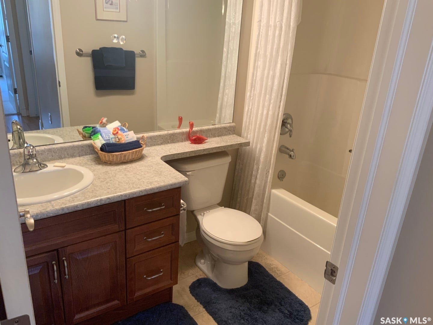 Bathroom featuring a vanity with a single basin sink, a stone-finish countertop, dark wood-finish cabinetry, a toilet, and a bathtub with shower
