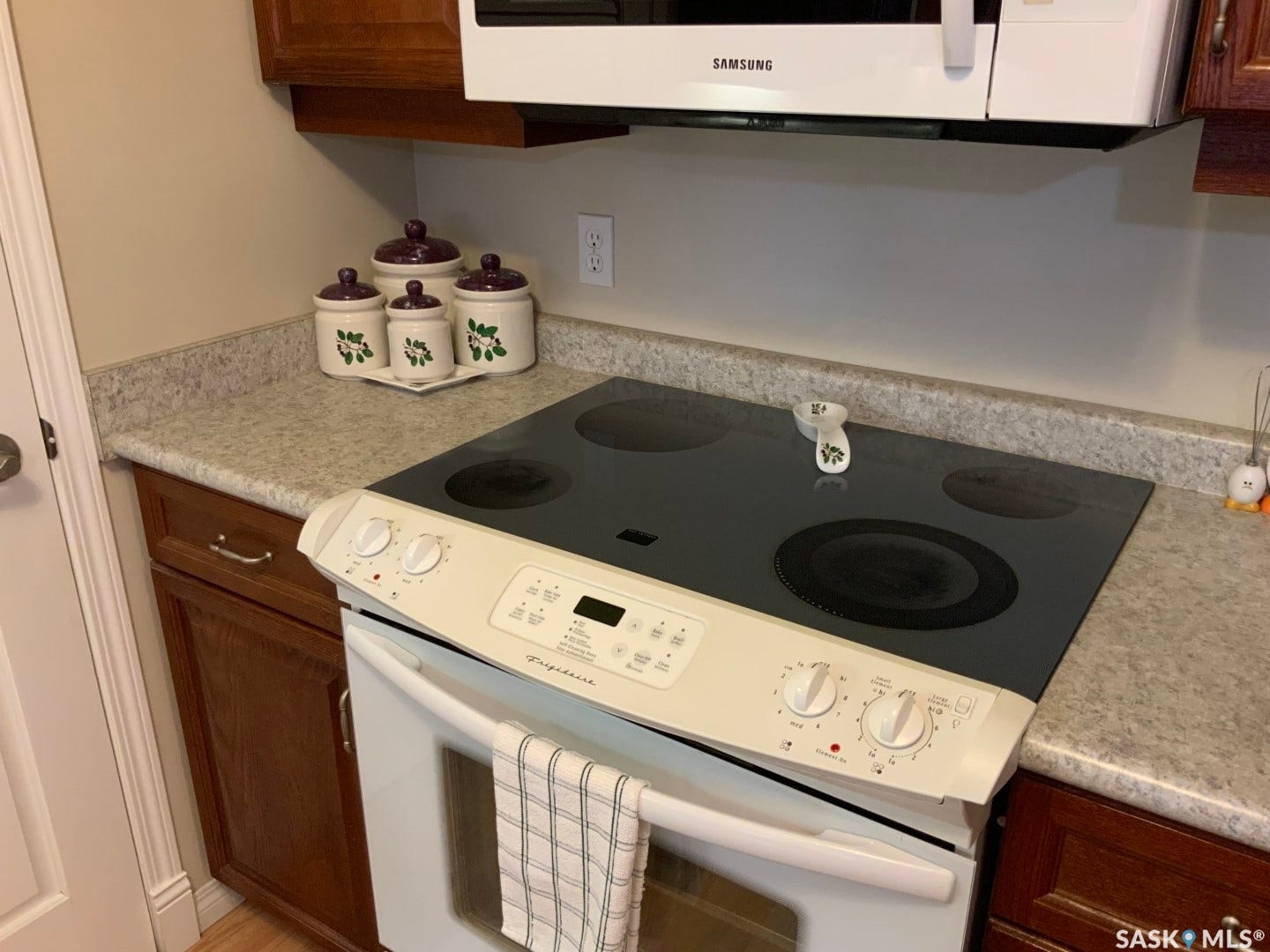 Hardwood cabinetry, stone-look countertops, over-the-range microwave, and electric cooktop