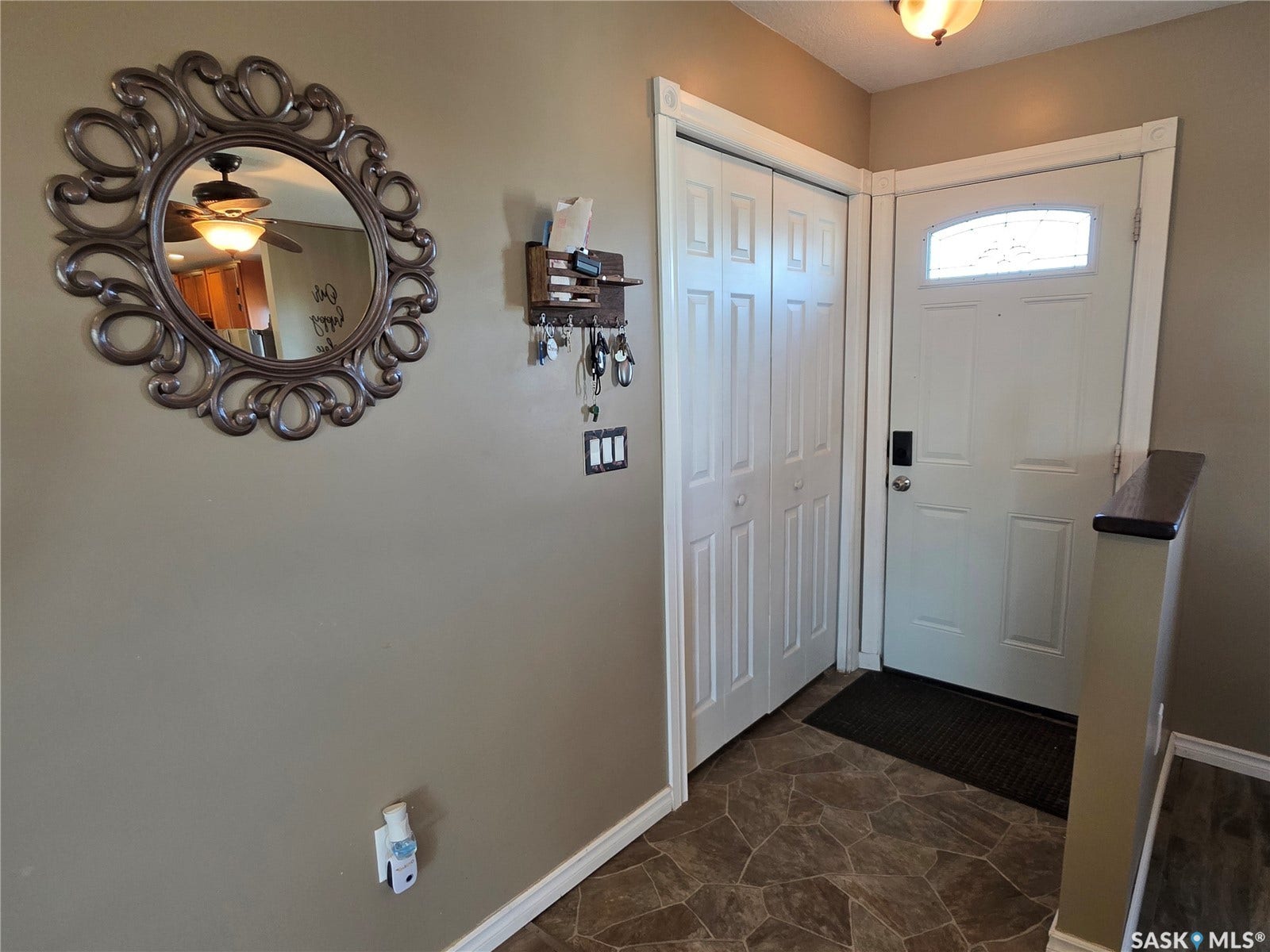 Entryway featuring a decorative front door with an arched window, bi-fold closet doors, a flush-mount ceiling light, and patterned flooring