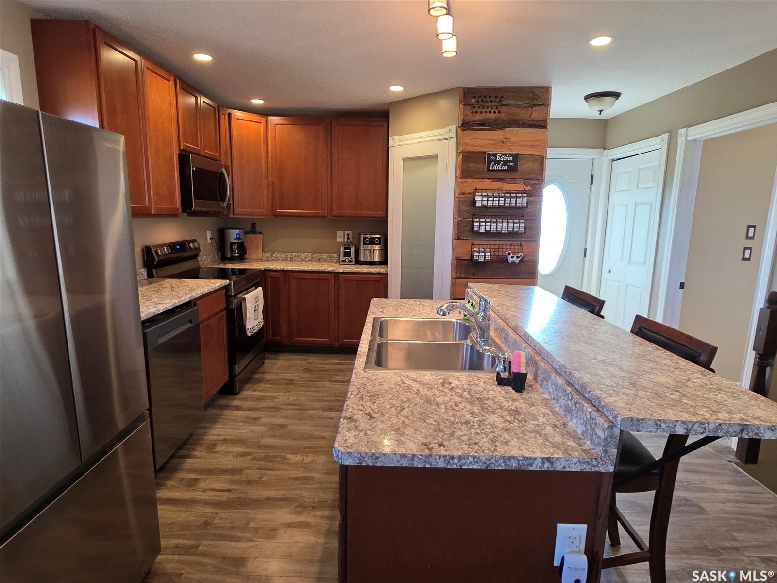 Stainless steel appliances, laminate flooring, recessed lighting, double basin sink, and a breakfast bar