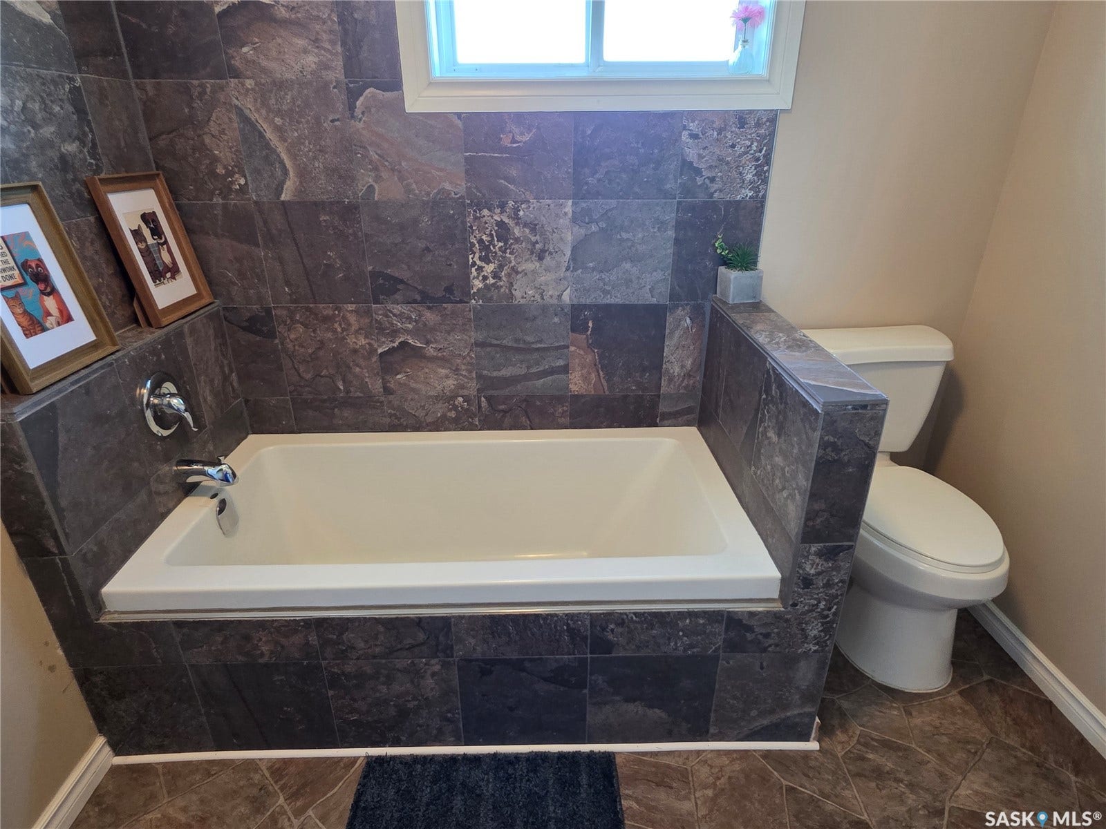 Built-in bathtub, surrounded by dark-toned tile