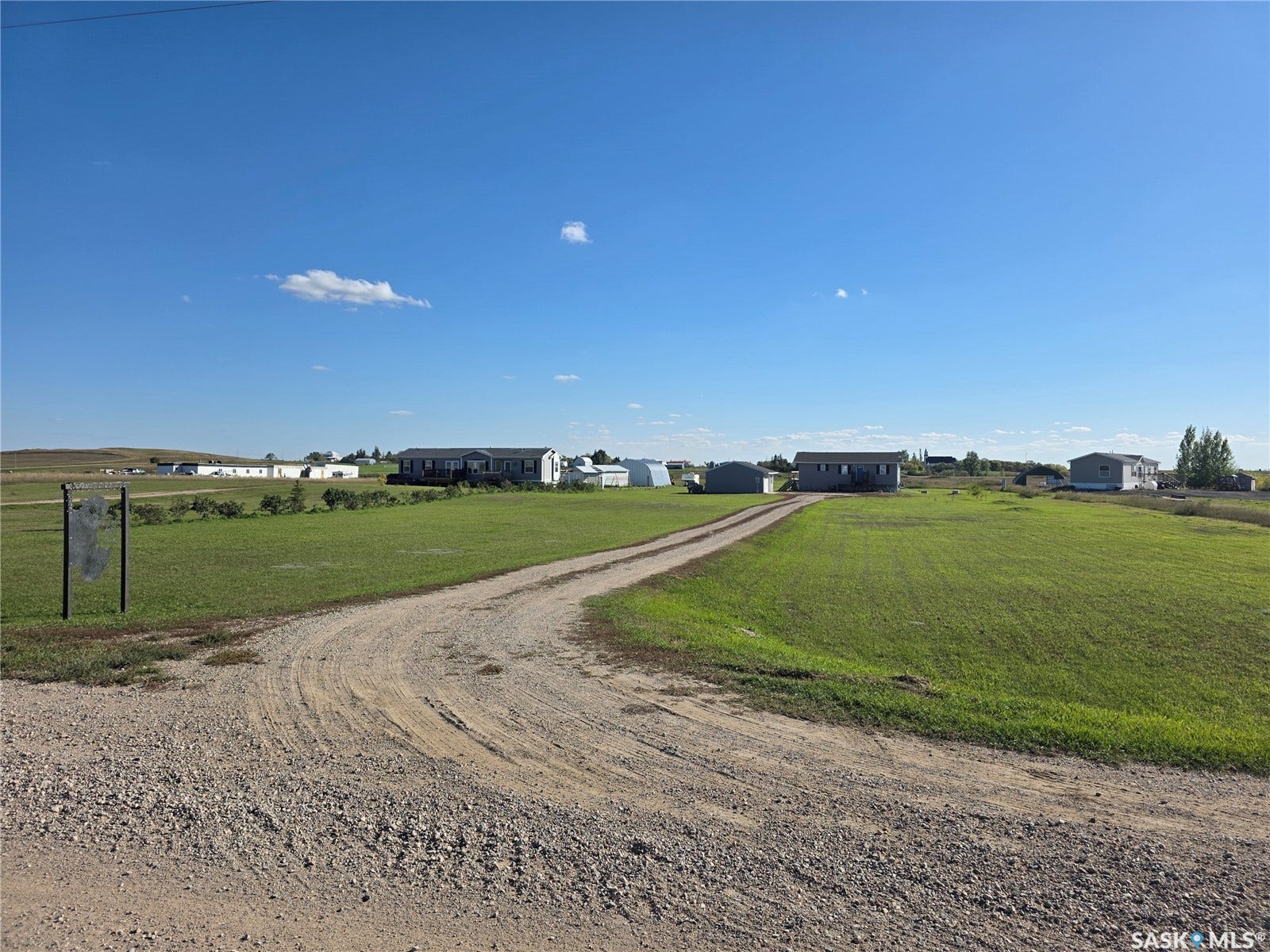 Expansive green landscape with a gravel driveway and clear skies