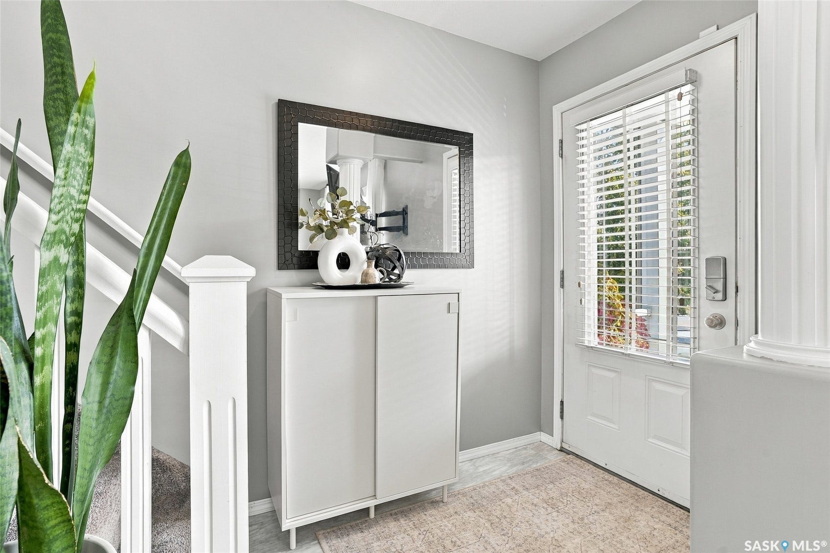 Entryway featuring a white door with integrated blinds, a decorative mirror, and a built-in storage cabinet