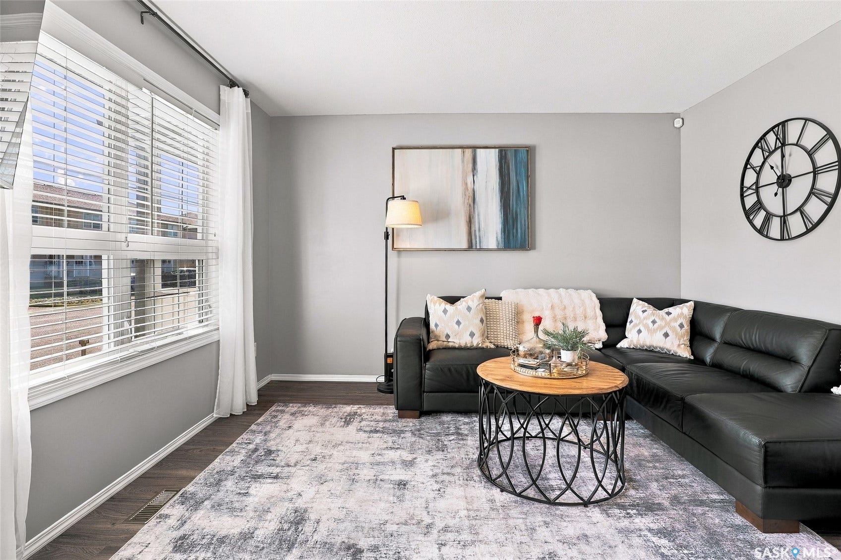 Wood-finish flooring with a large window featuring blinds and curtains