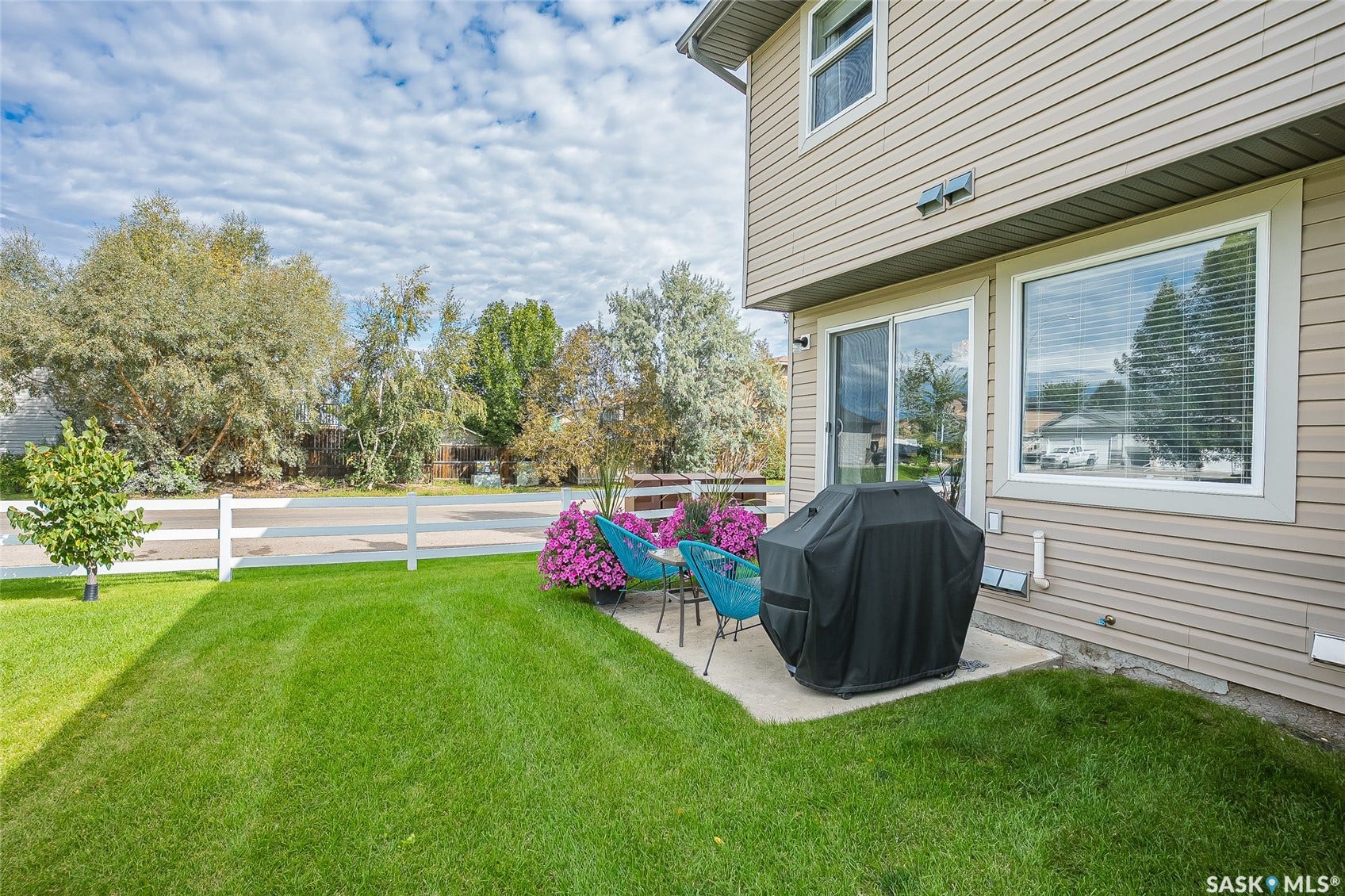 Expansive lawn area, concrete patio, sliding glass door, double-paned window, and horizontal siding
