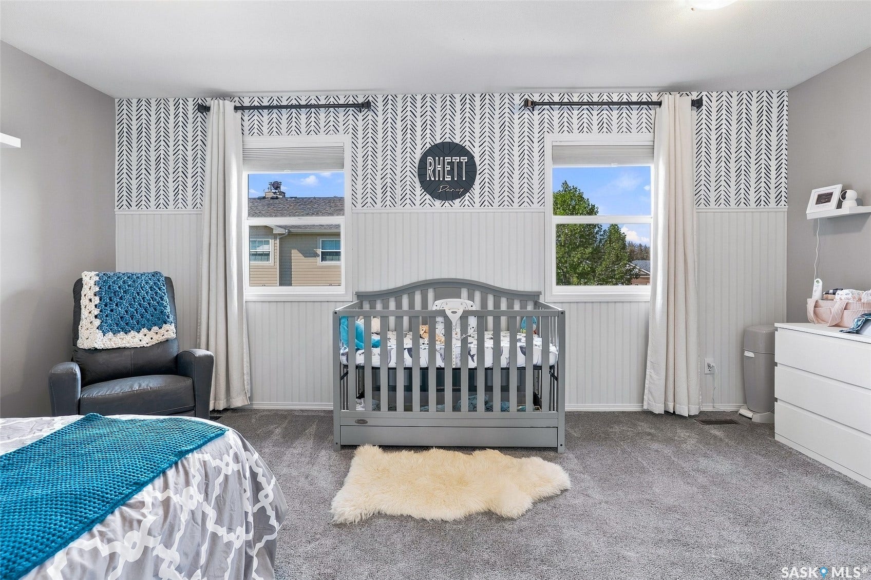 Neutral gray carpeting, two windows with white trim, wall paneling, and patterned wallpaper