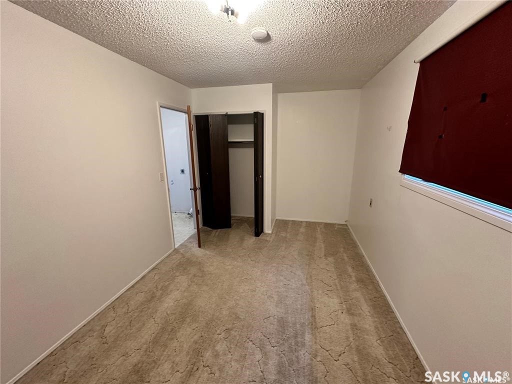 Textured ceiling, wall-to-wall carpeting, and a built-in closet with double dark wood doors