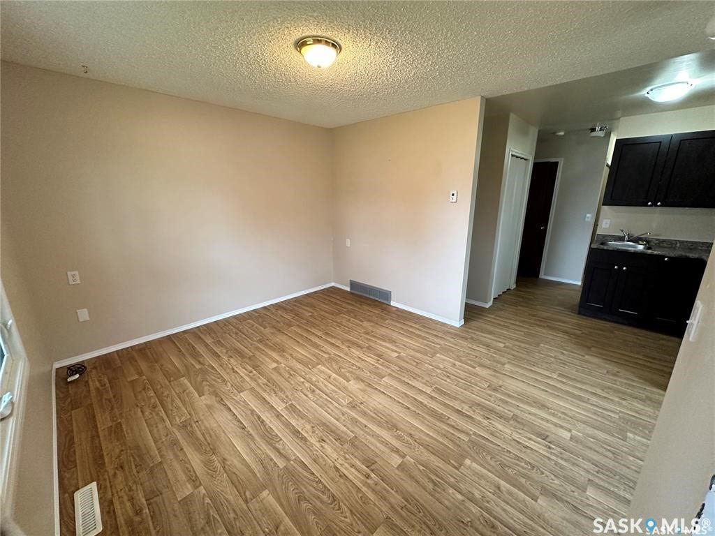 Wood-finish flooring throughout, neutral painted walls, and textured ceiling
