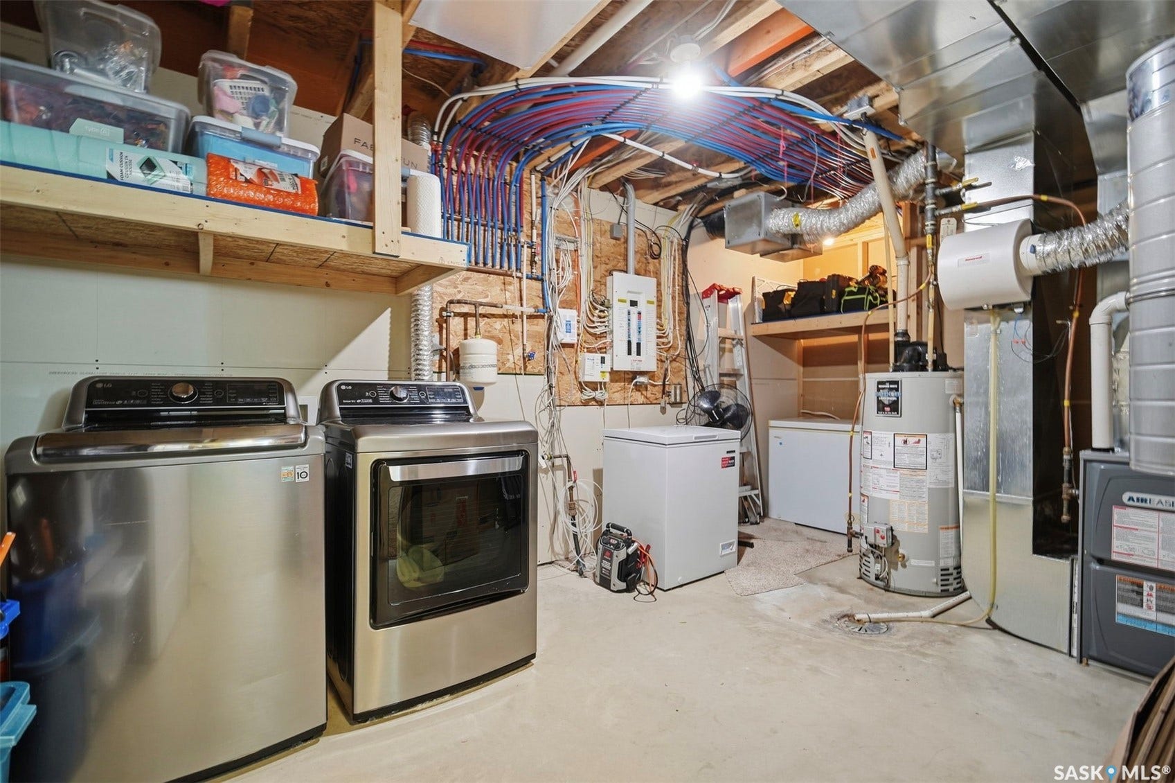 Utility room with exposed ceiling joists, overhead wooden shelving, and a concrete floor