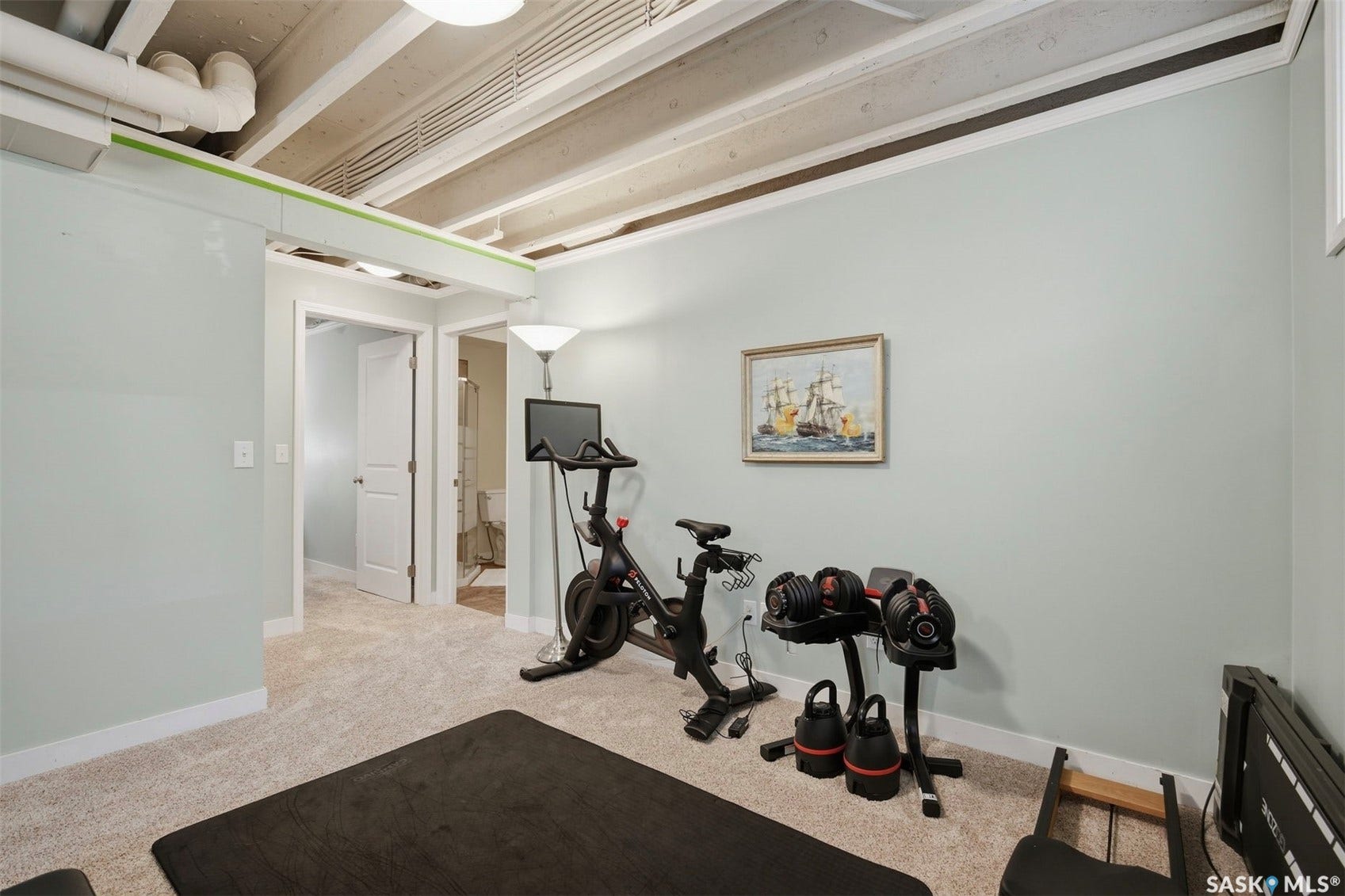 Carpeted room with light-colored walls and exposed ceiling beams