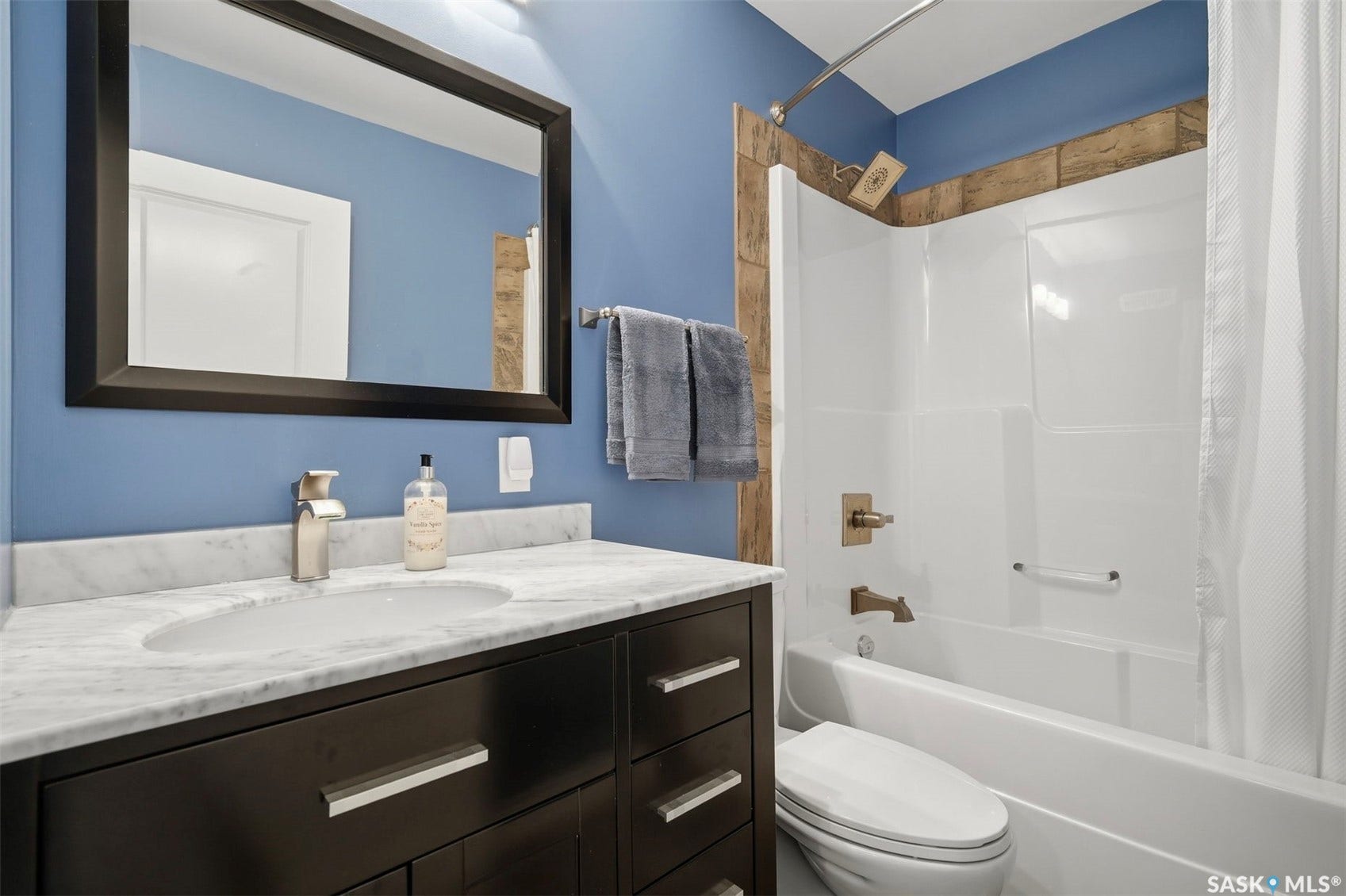 Dark wood-finish vanity with drawer storage, sleek marble-finish countertop, undermount sink, and brushed nickel faucet