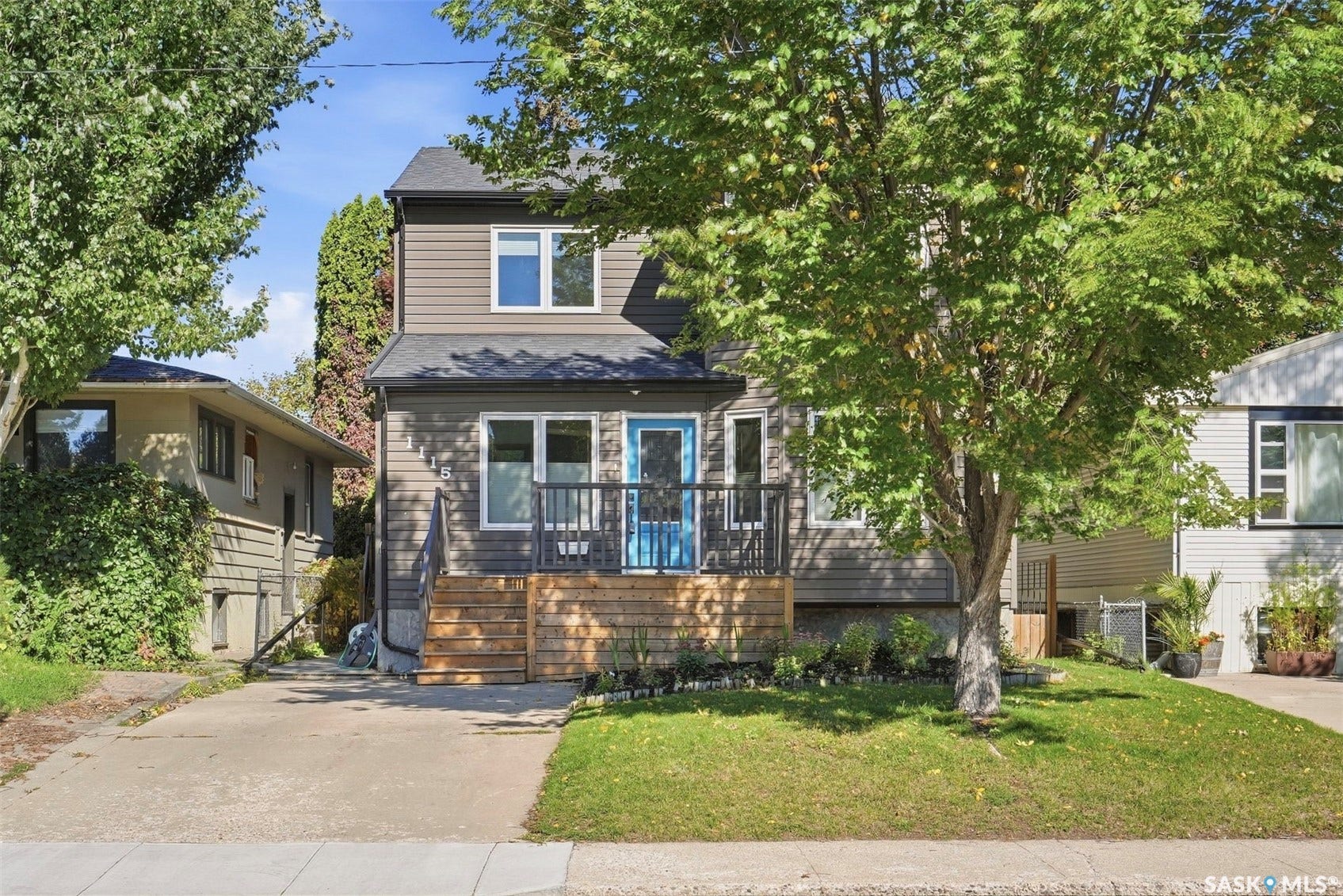 Two-story exterior with horizontal siding, a prominent wood deck, and a vibrant blue entry door