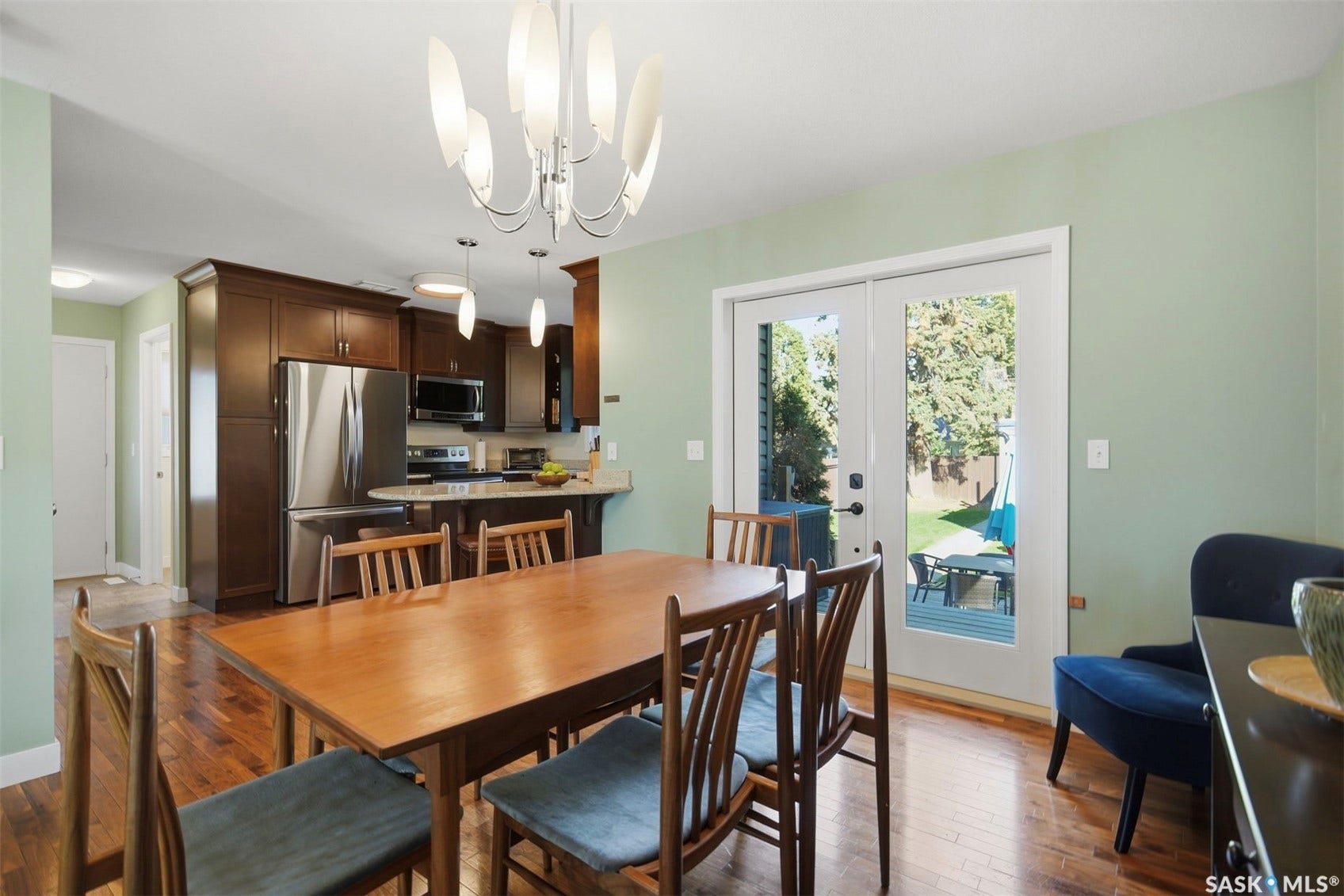 Hardwood flooring, French doors with exterior access, contemporary chandelier, dark wood cabinetry, and stainless steel appliances