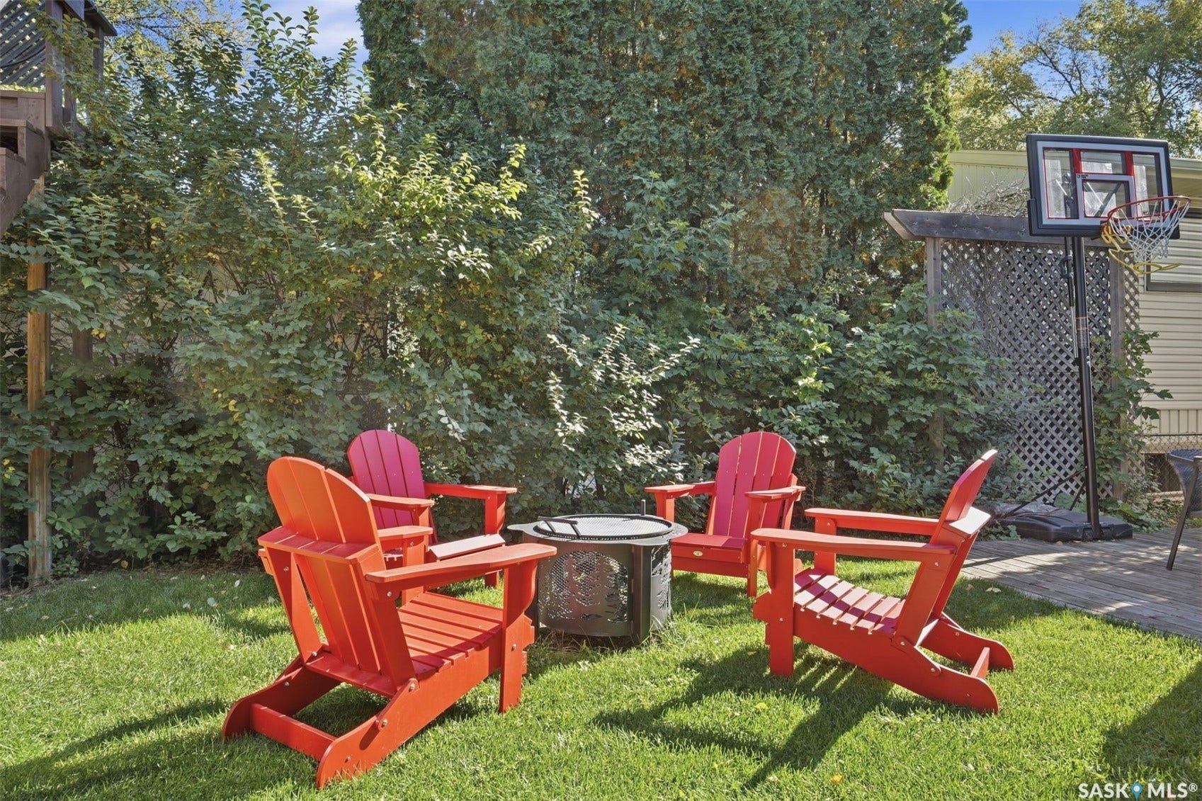 Manicured lawn with a fire pit area, surrounded by mature trees and shrubs