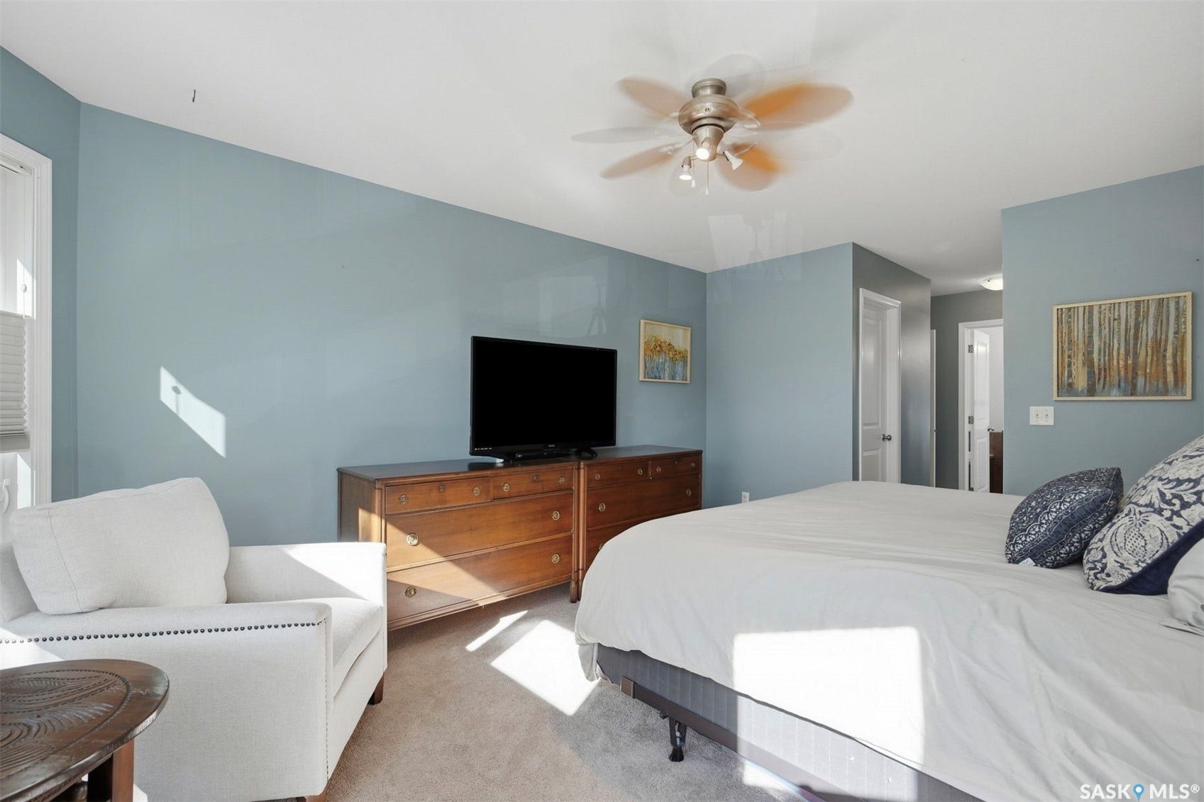 Recessed window with blinds, ceiling fan with integrated lighting, wood-finish flooring, and light blue wall paint