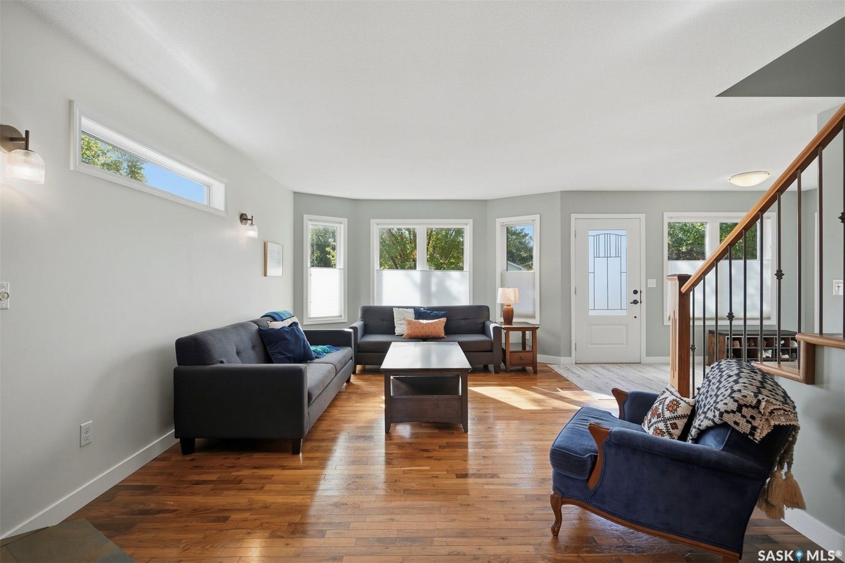 Hardwood flooring, multiple windows, transom window, recessed entryway, and a staircase with wood and metal railings
