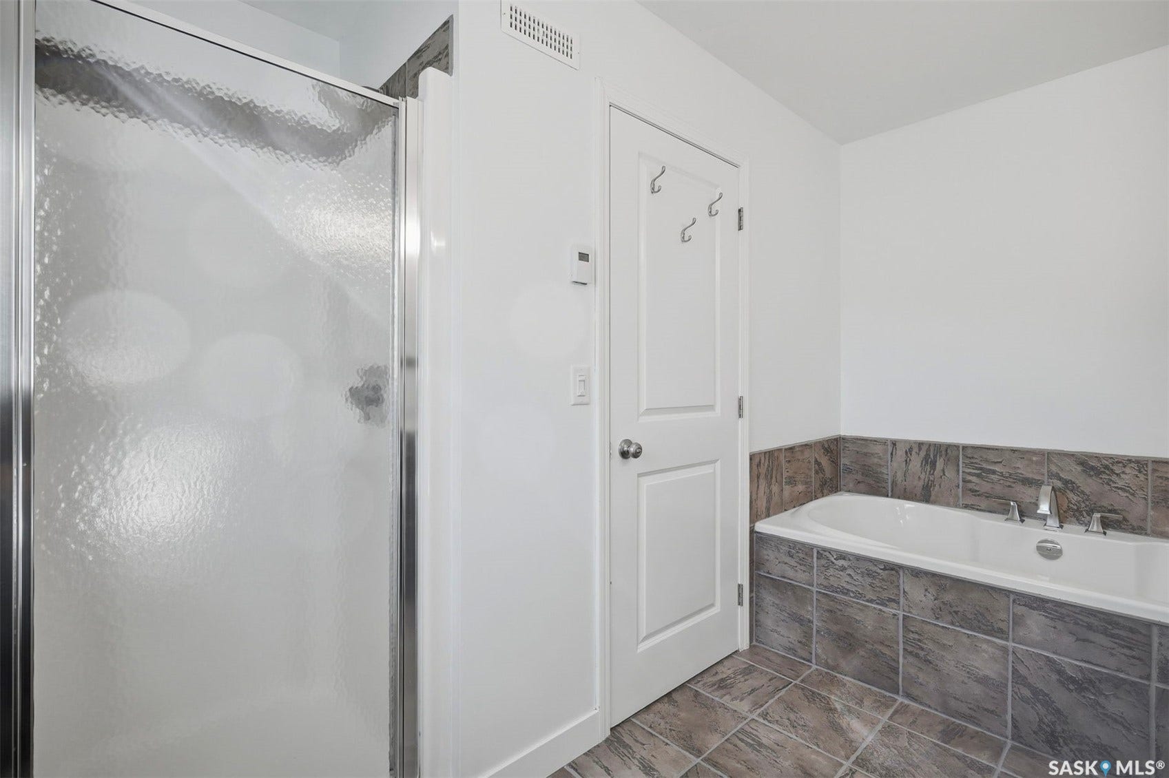 Enclosed shower with textured glass, soaking tub with tile surround, and tile flooring