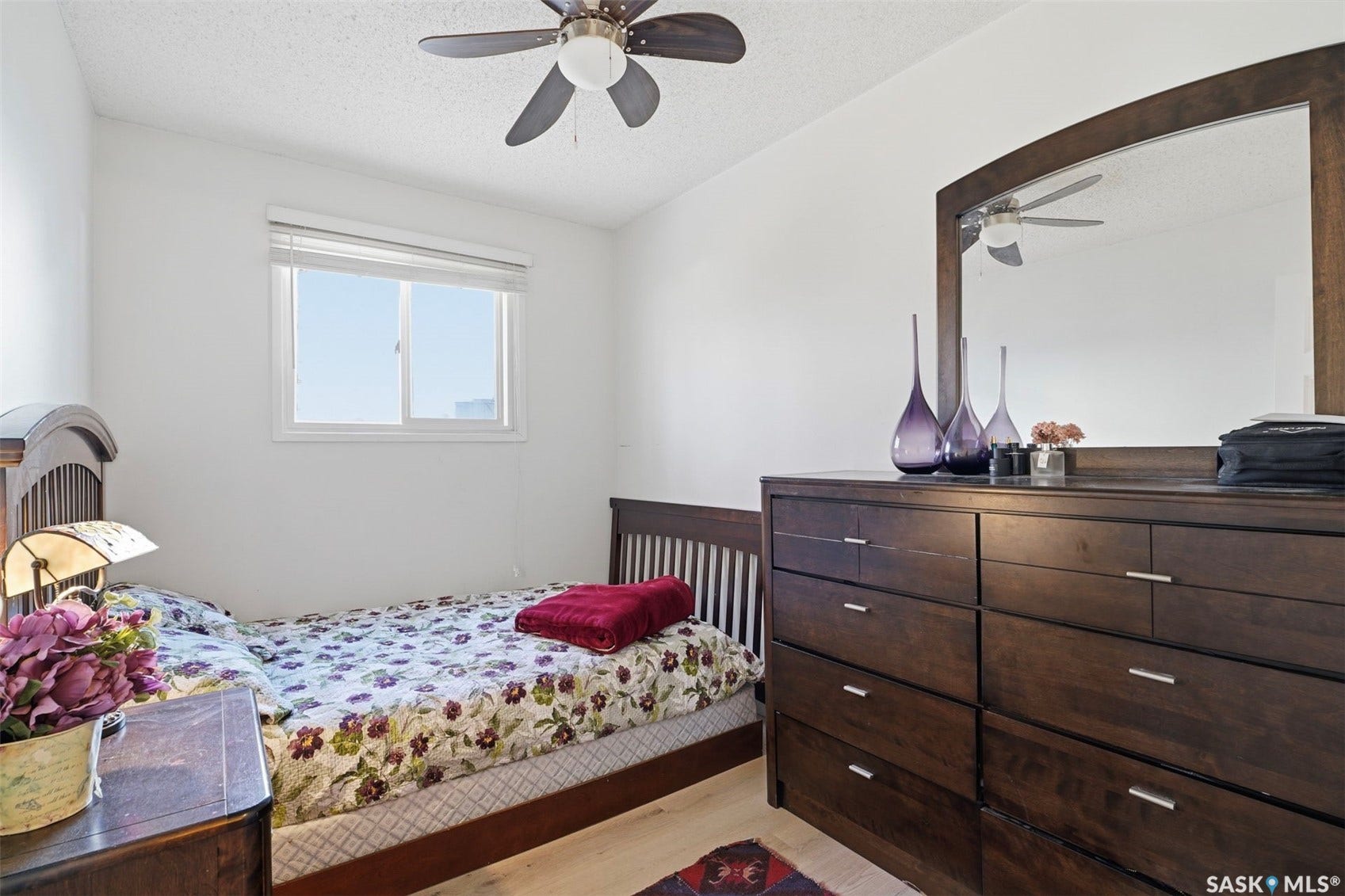 White walls with a window featuring blinds, a ceiling fan with integrated lighting, and light wood-finish flooring