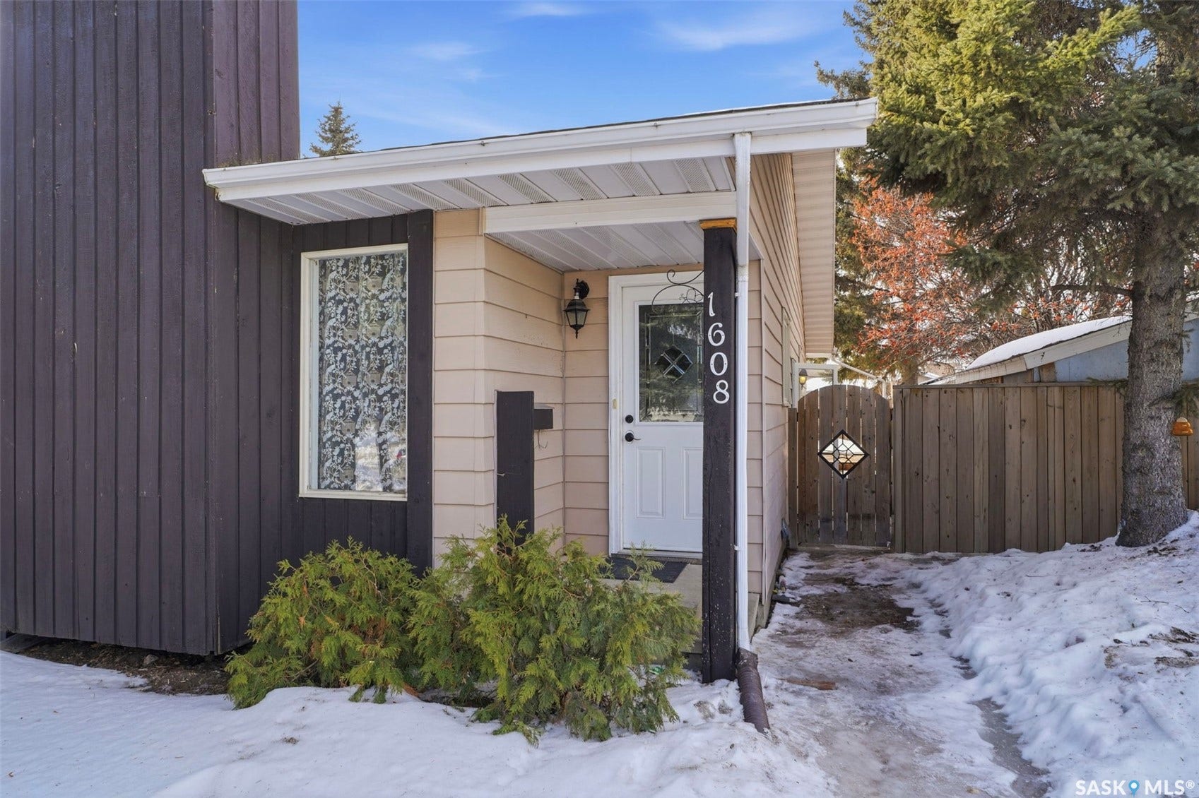 Front entry featuring a covered porch, white paneled door, and exterior sconce lighting