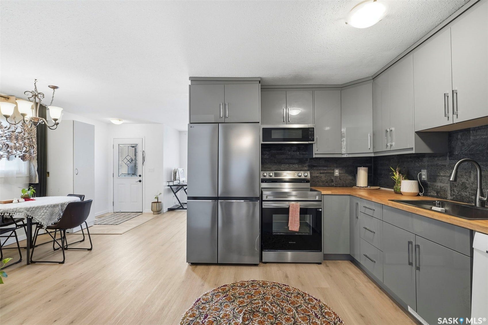 Contemporary kitchen featuring stainless steel appliances, grey cabinetry, and wood-finish countertops