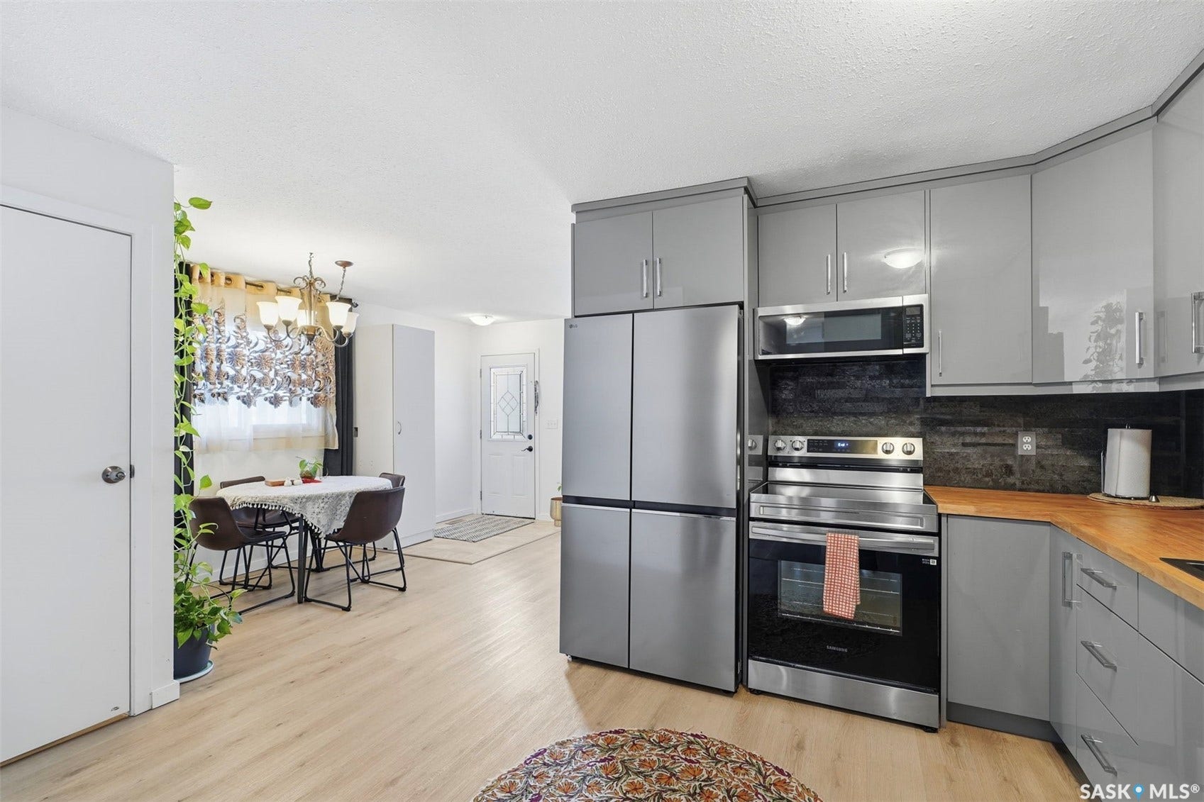 Contemporary kitchen featuring stainless steel appliances, grey cabinetry, and wood-finish countertops